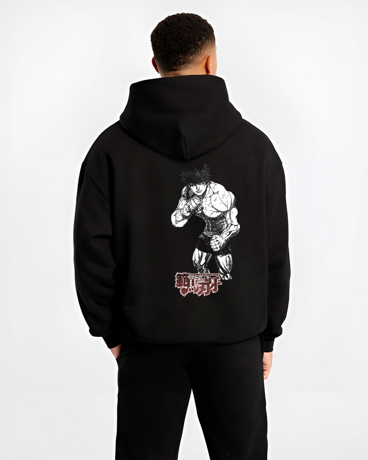 Black hoodie worn by a male model, back view, featuring Baki Hanma Son of Ogre shonen battle inspired anime design with retro manga artwork details.
