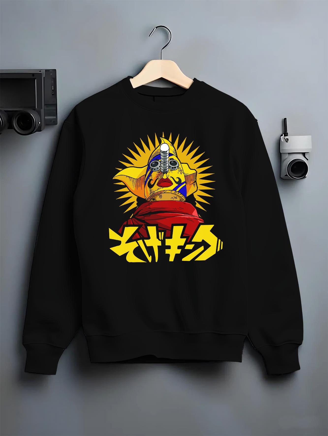 Black crewneck sweatshirt on hanger against grey wall, featuring urban fashion back design with manga idol, bold sunburst, and Japanese text.
