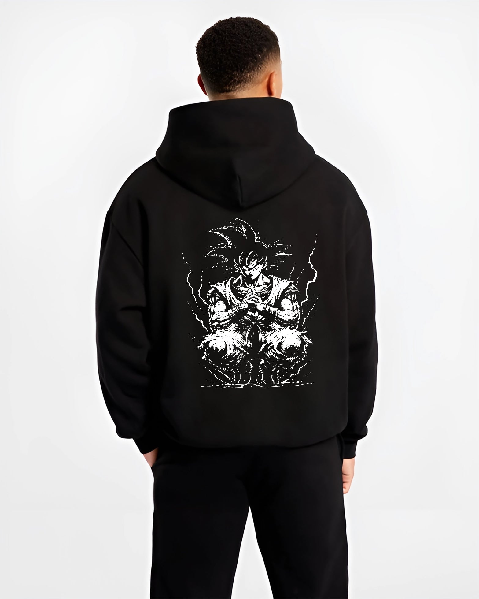 Black hoodie worn by a male model, back view, featuring Dragon Ball Goku retro manga graphic in meditation pose with glowing aura in anime poster inspired style.