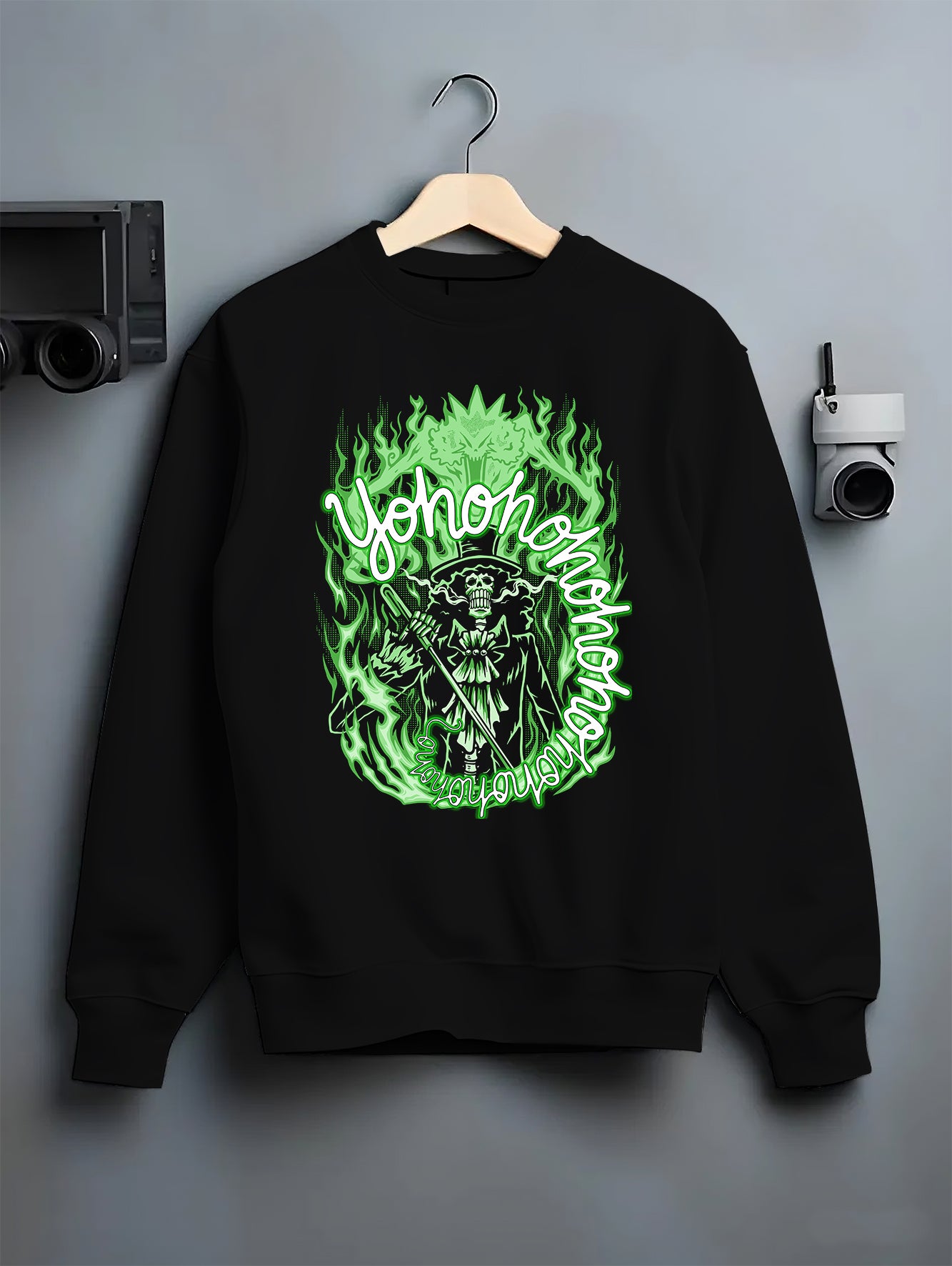 Black crewneck sweatshirt on a hanger against a grey wall, featuring One Piece Brook dark manga panel artwork with glowing green anime poster inspired design.