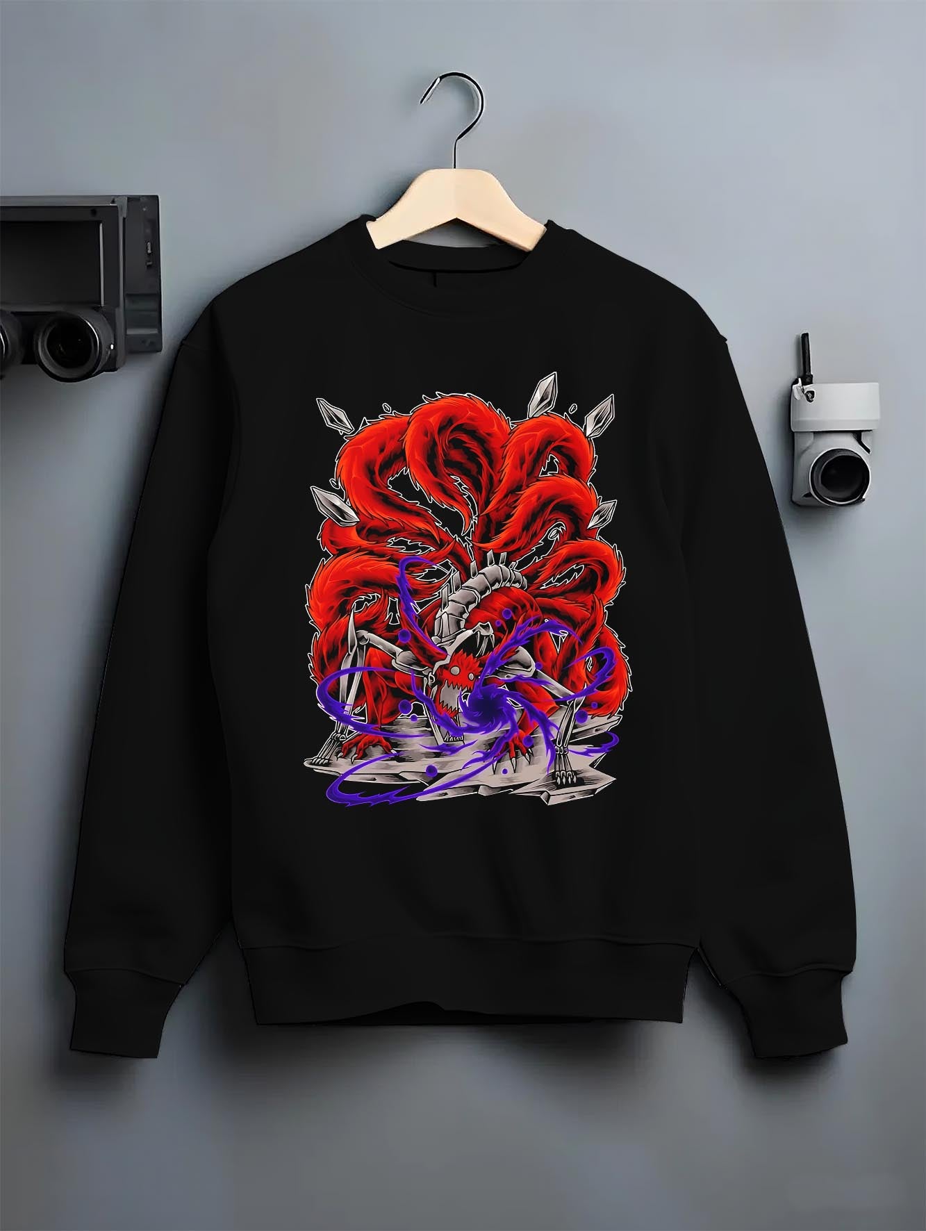 Black crewneck sweatshirt on a hanger against a grey wall, featuring Naruto Kurama Nine-Tails anime poster inspired design with bold chakra aura and retro manga style.