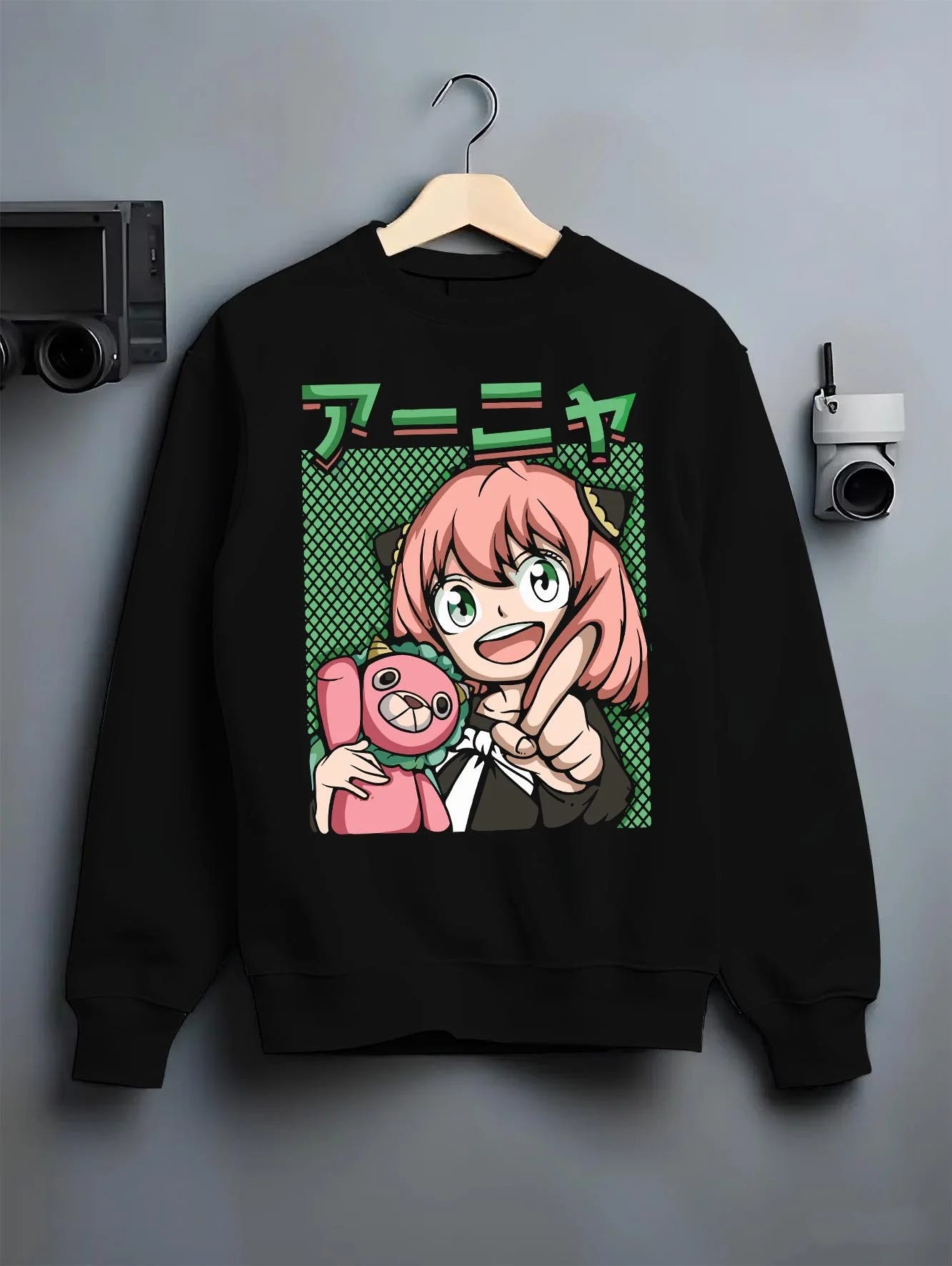 Black crewneck sweatshirt on hanger with Anya Forger Hoodie Spy x Family Retro Pop Art Smile graphic bold anime graphic.