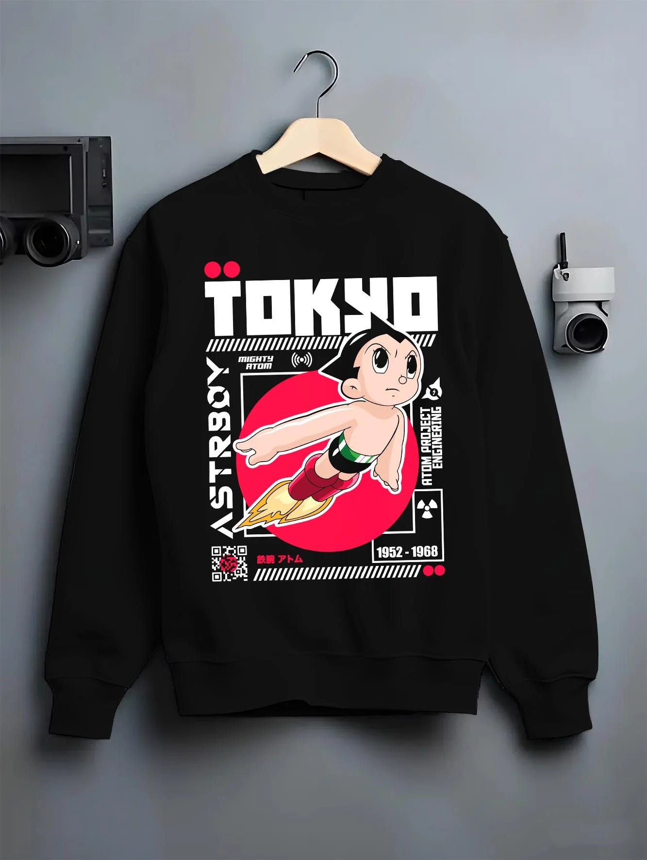 Black crewneck sweatshirt on hanger with Astro Boy Hoodie Retro Tokyo Anime Robot Hero Poster graphic bold anime graphic.