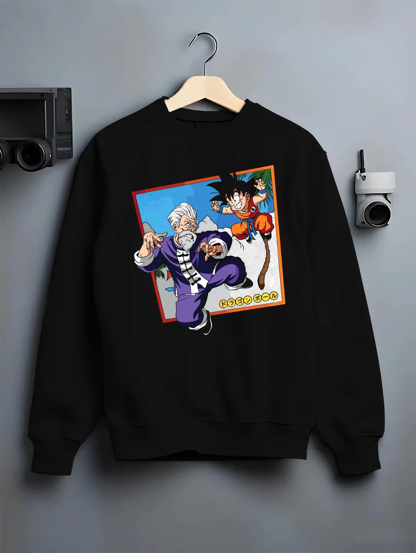 Black crewneck sweatshirt on hanger with Dragon Ball Hoodie Goku Training Retro Anime Panel graphic streetwear graphic.