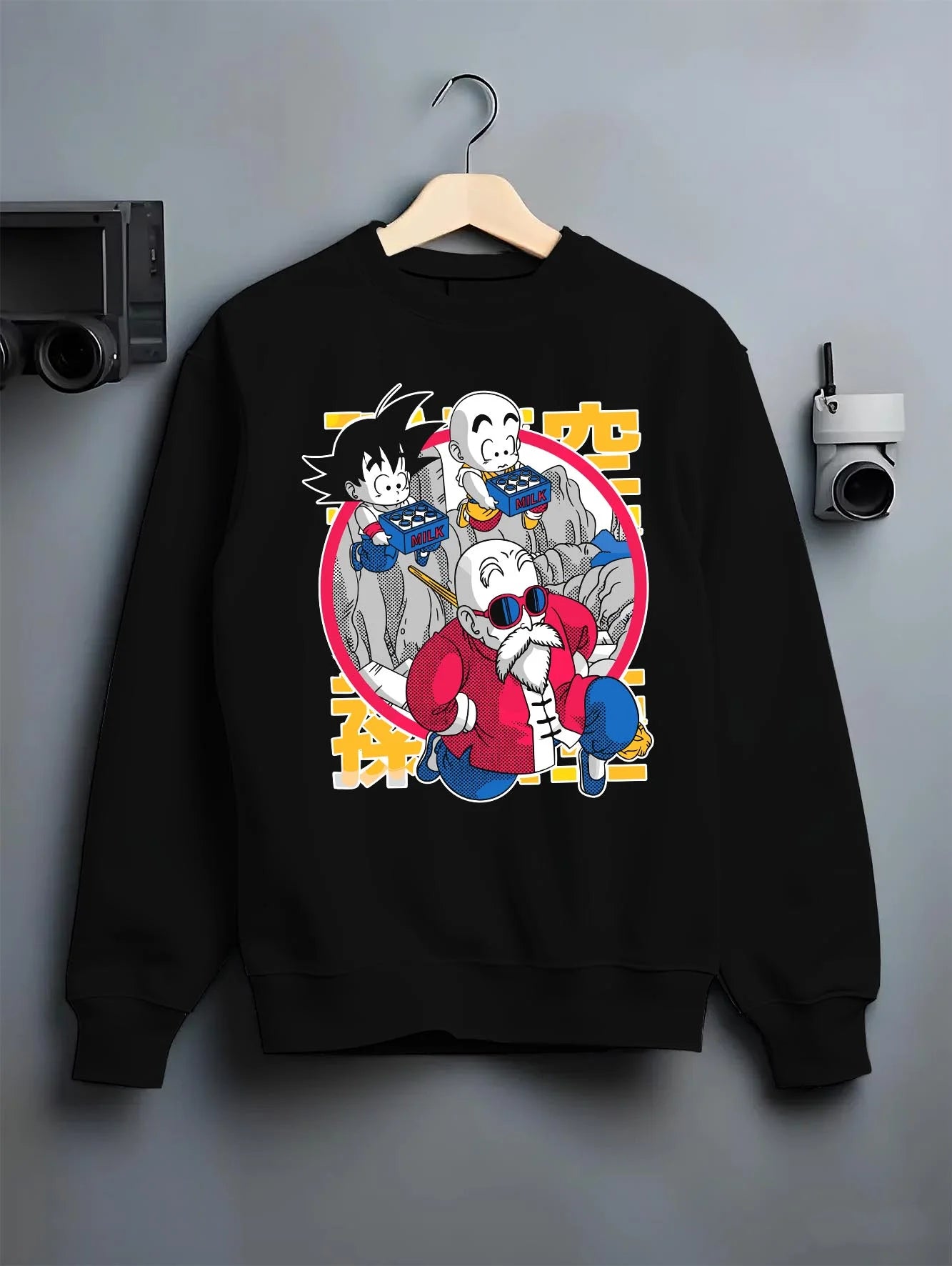 Black crewneck sweatshirt on hanger with Dragon Ball Hoodie Krillin Retro Training White Gi graphic bold anime graphic.