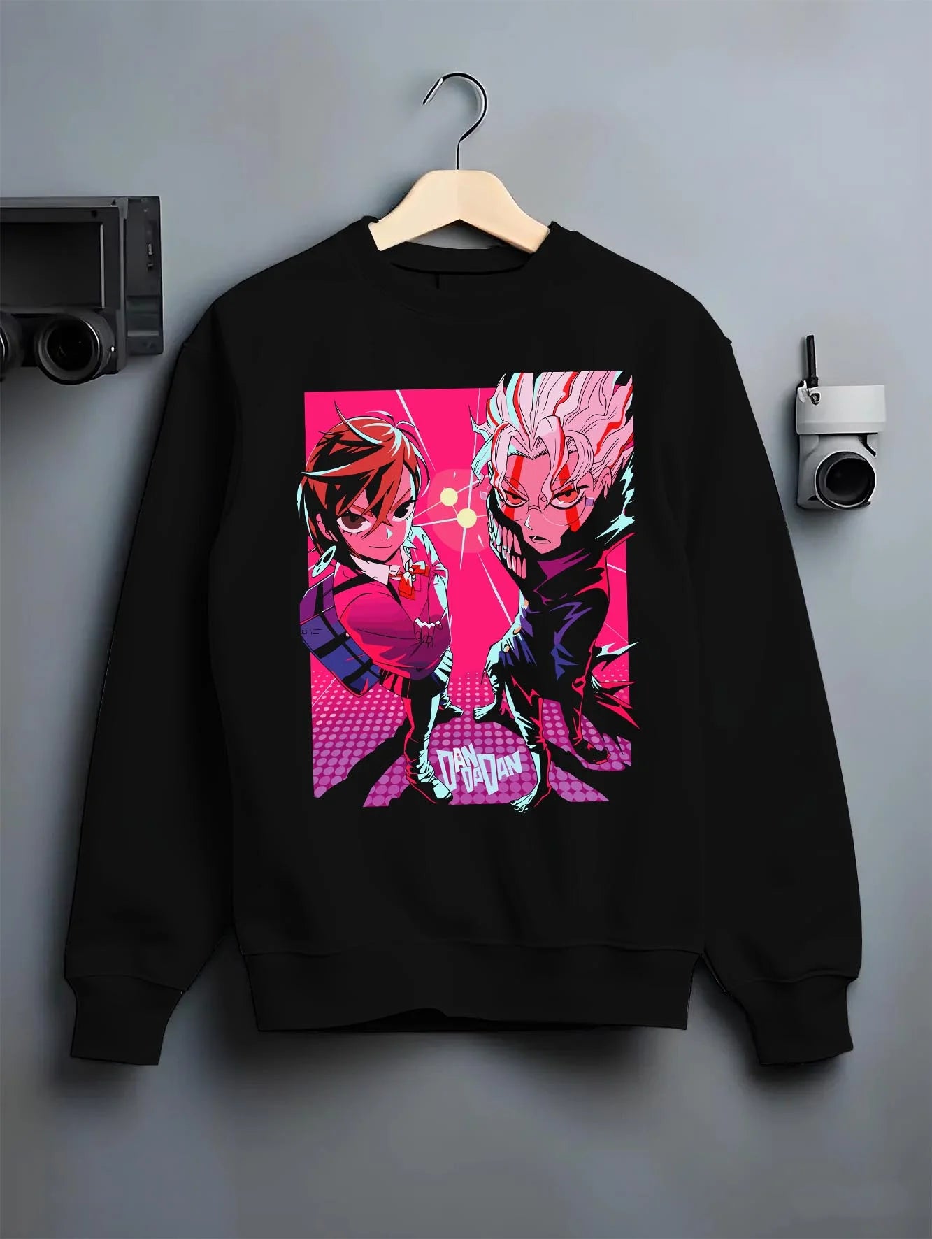 Black crewneck sweatshirt on hanger with Dandadan Duo Hoodie Paranormal Adventure Retro Anime graphic streetwear graphic.