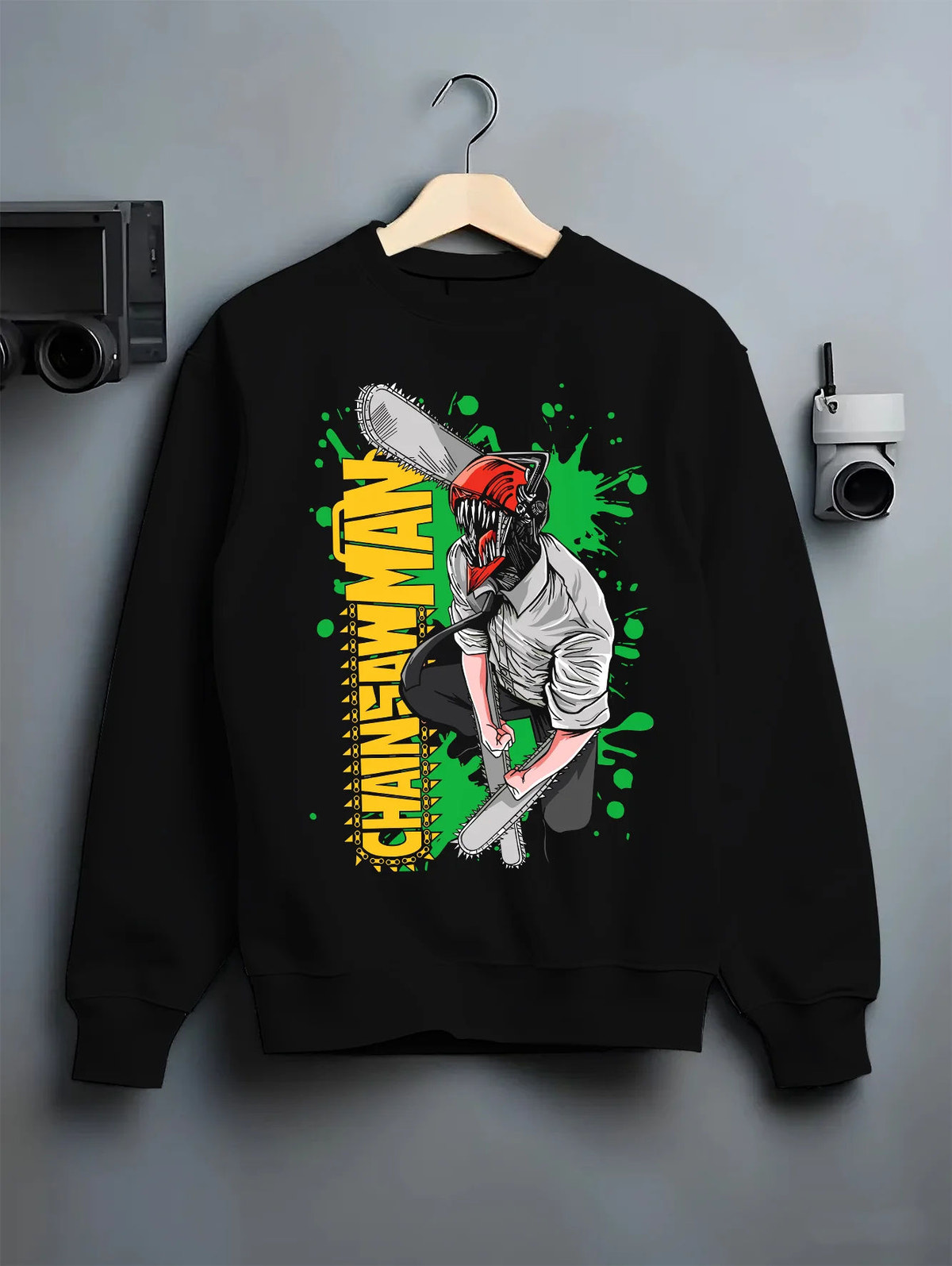 Black crewneck sweatshirt on hanger showing Denji transformed from Chainsaw Man: chainsaw head and shirt, green background