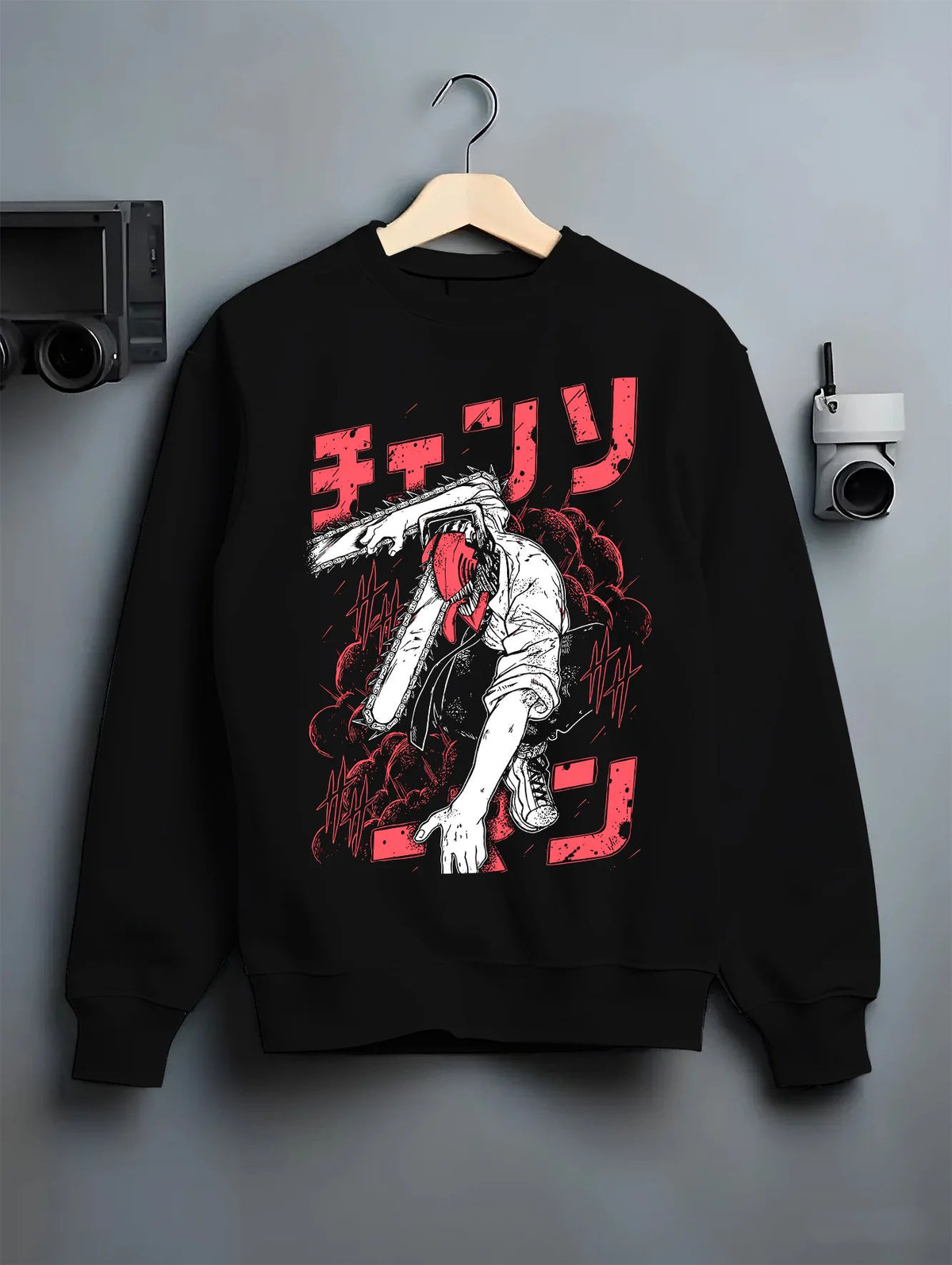 Black crewneck sweatshirt on hanger showing Denji transformed from Chainsaw Man: black-white chainsaw head, red lettering
