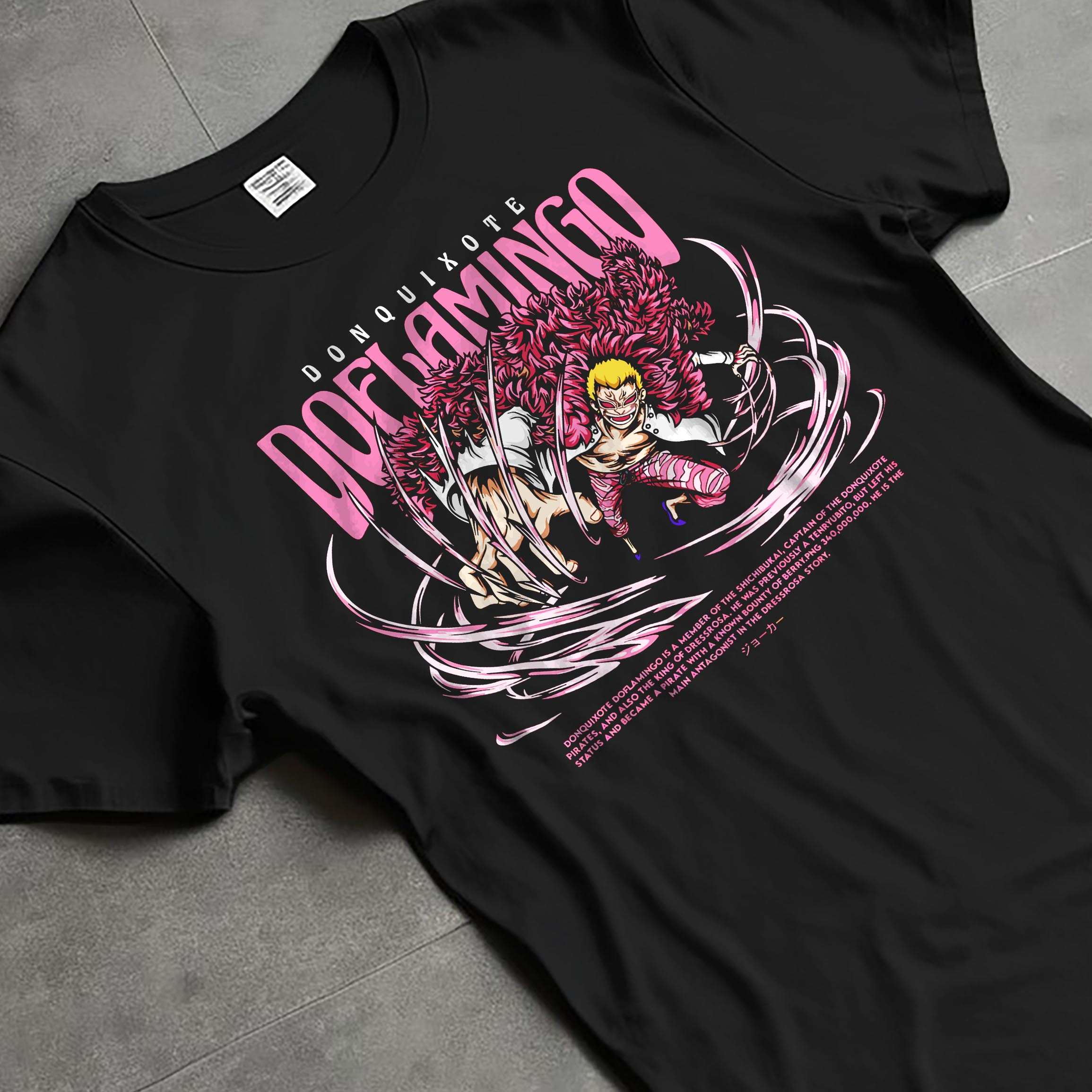 Black T-shirt laid flat with natural fabric folds, featuring One Piece Doflamingo anime poster inspired design with pink feather coat in retro manga battle artwork style.