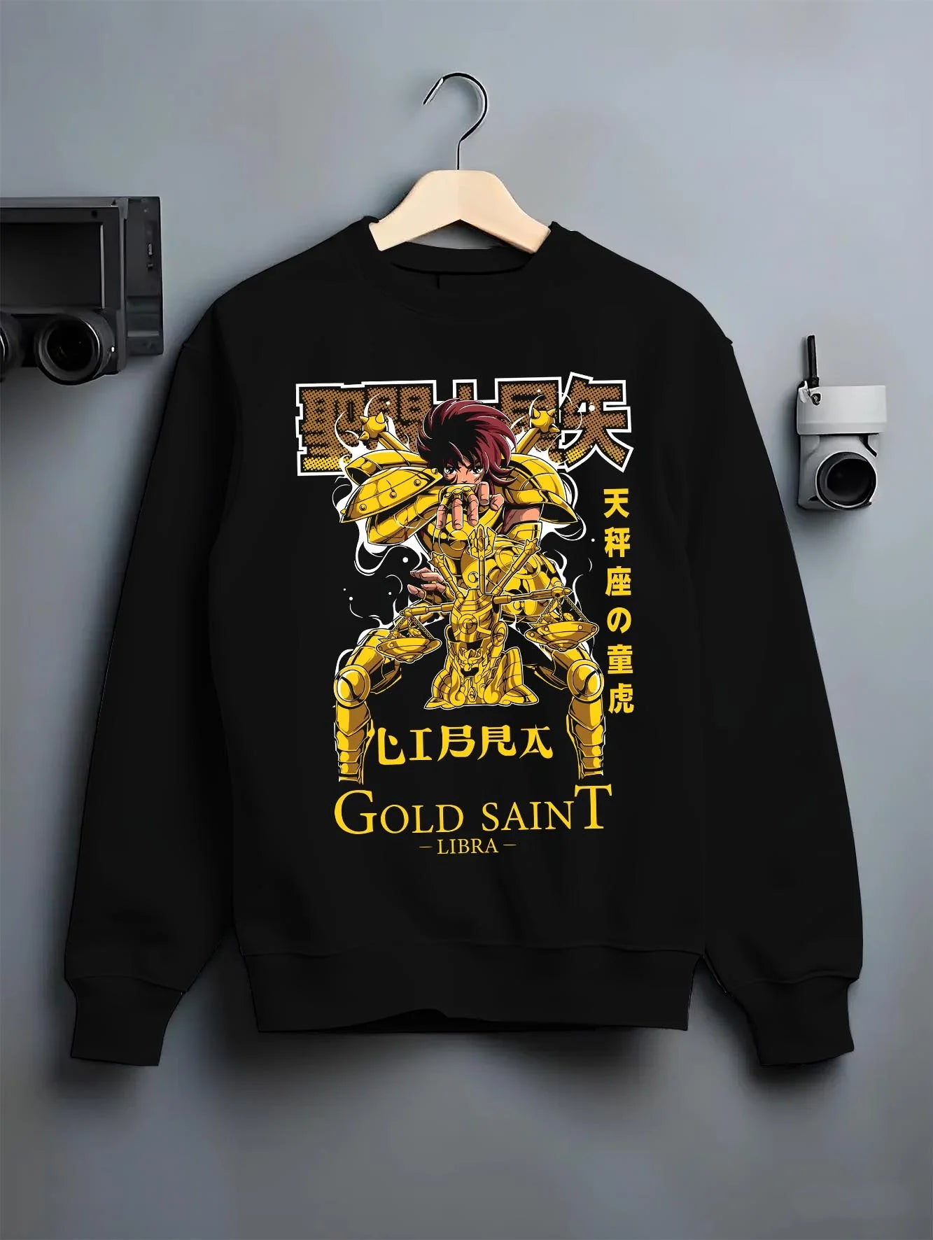 Black crewneck sweatshirt on hanger with Libra Hoodie Saint Seiya Gold Saint Armour Retro graphic premium wear.