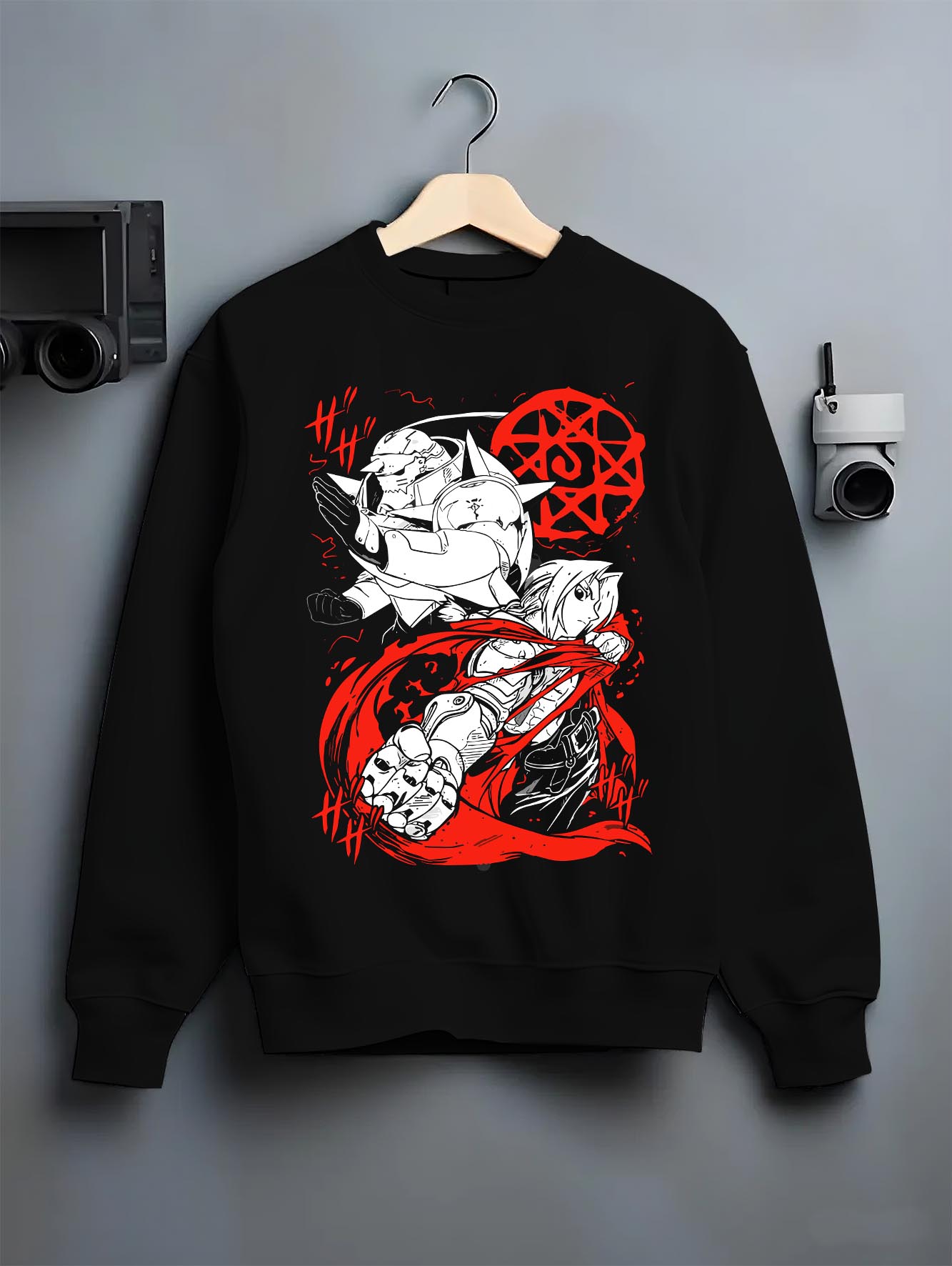 Black crewneck sweatshirt on a hanger against a grey wall, featuring Fullmetal Alchemist Edward and Alphonse anime poster inspired design with bold red alchemy circle retro manga artwork.