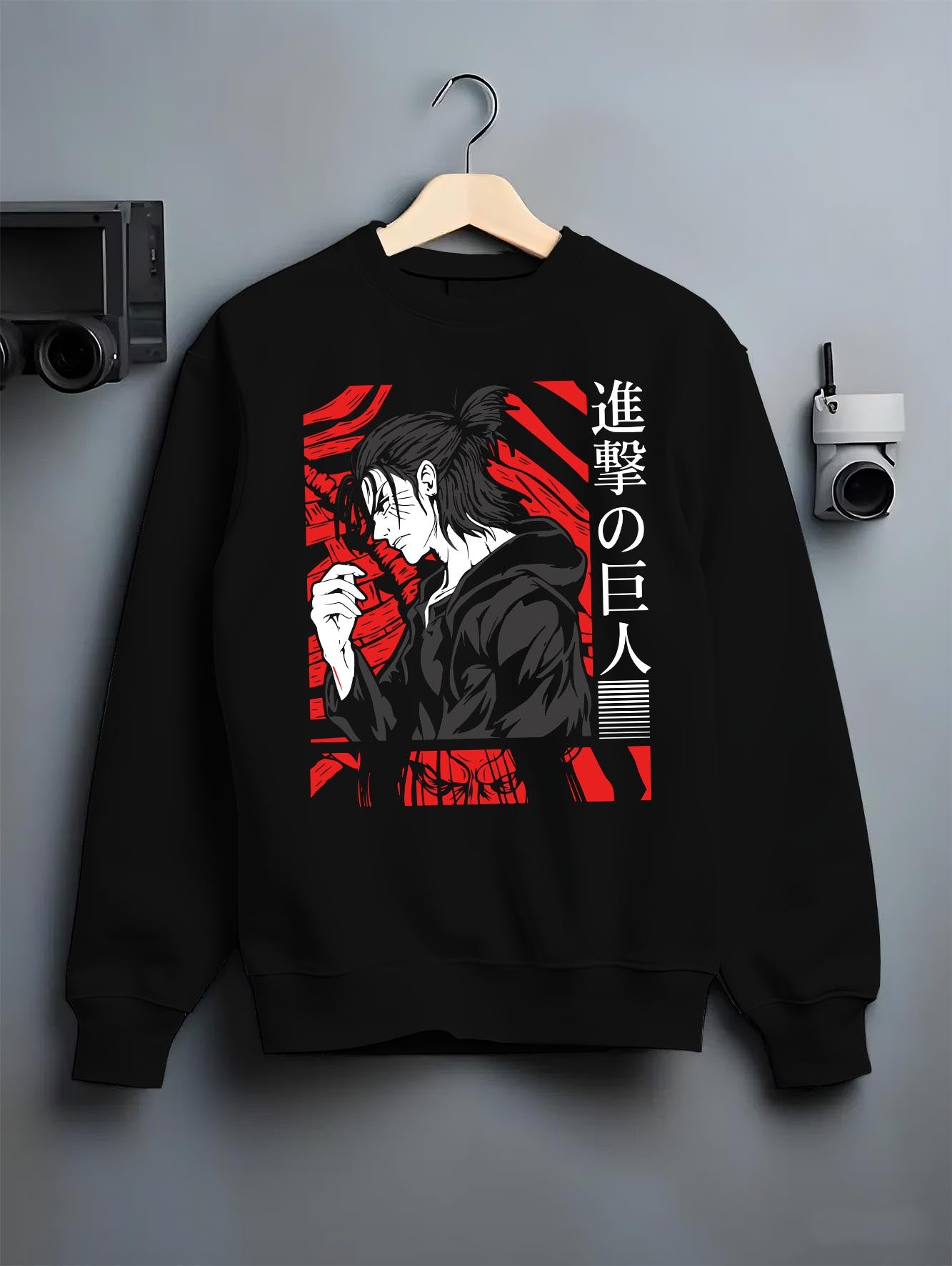 Black crewneck sweatshirt on a hanger against a grey wall, featuring Attack on Titan Eren Yeager anime poster inspired portrait graphic with retro manga style and red design.