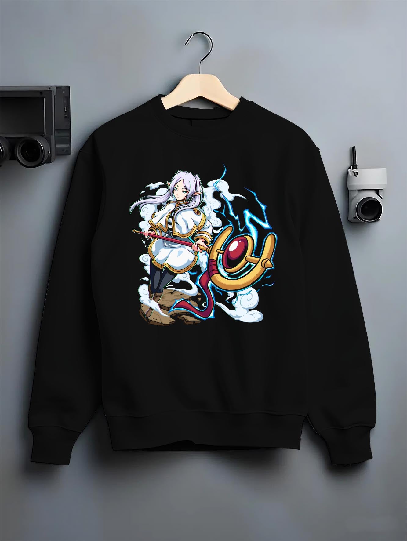 Black crewneck sweatshirt on a hanger against a grey wall, featuring Black Clover Mereoleona Japanese animation streetwear design with vibrant blue lightning effect.