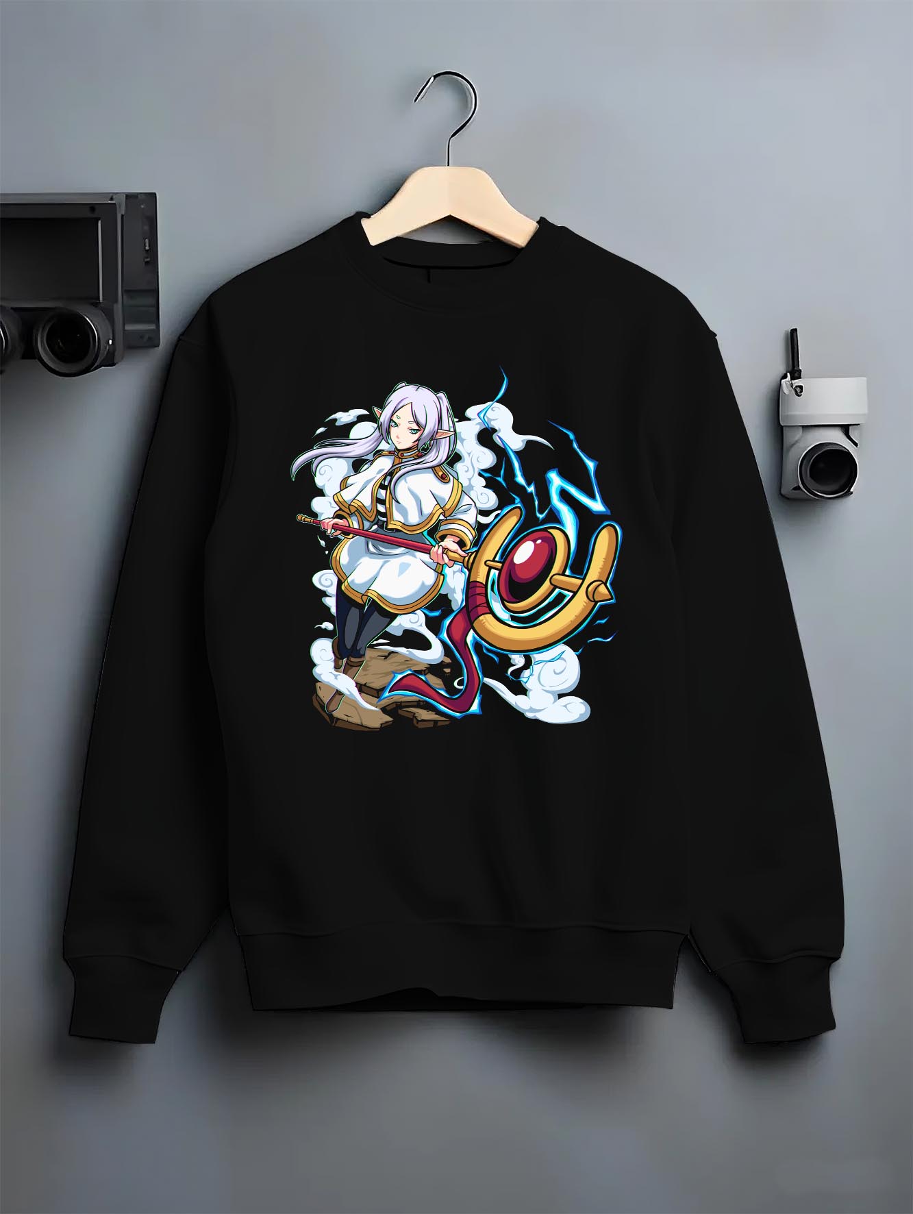 Black crewneck sweatshirt on a hanger against a grey wall, featuring Black Clover Mereoleona Japanese animation streetwear design with vibrant blue lightning effect.