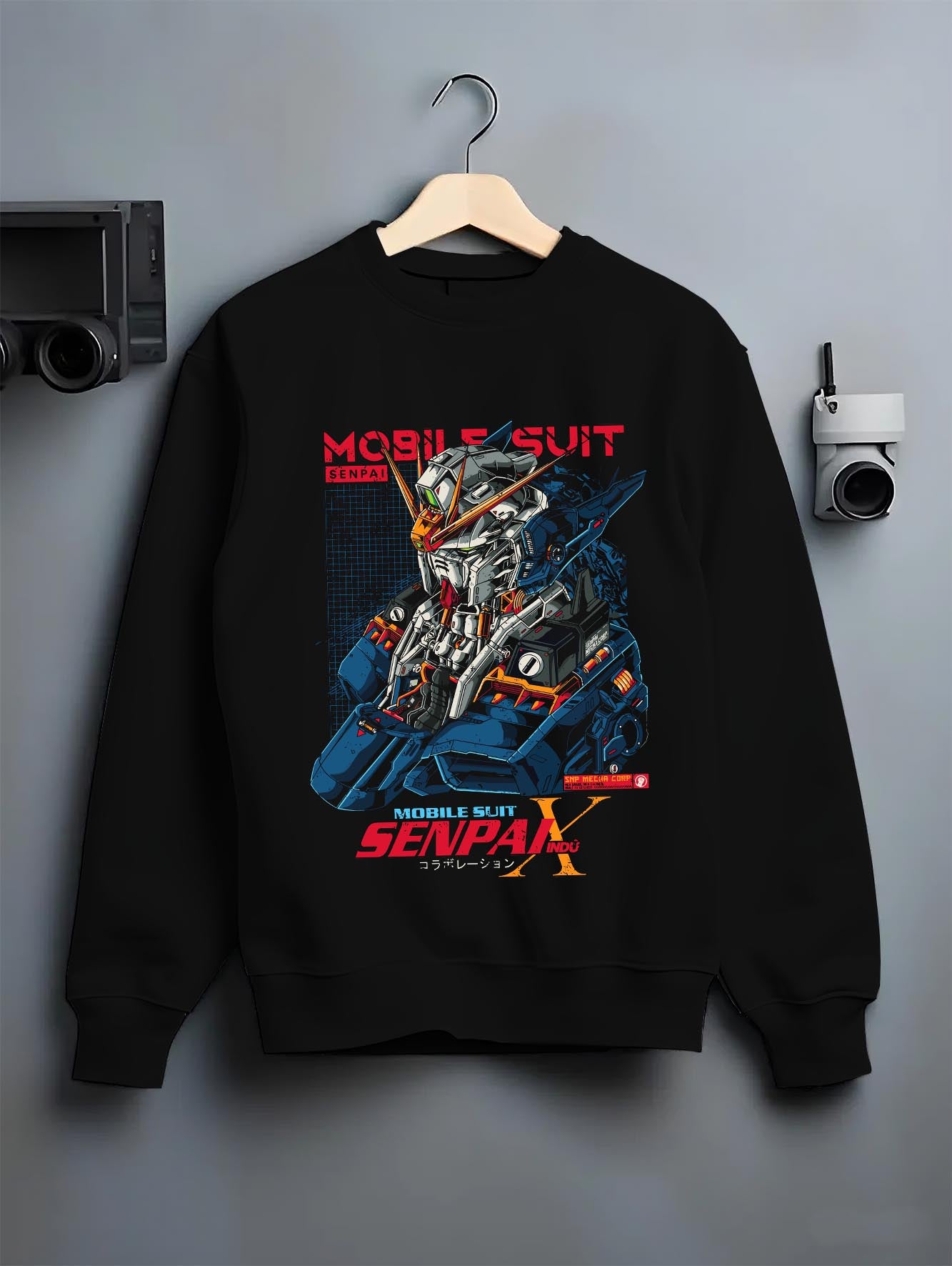Black crewneck sweatshirt on a hanger against a grey wall, featuring Mobile Suit retro mecha anime poster artwork with cyberpunk robotic style and bold futuristic design.