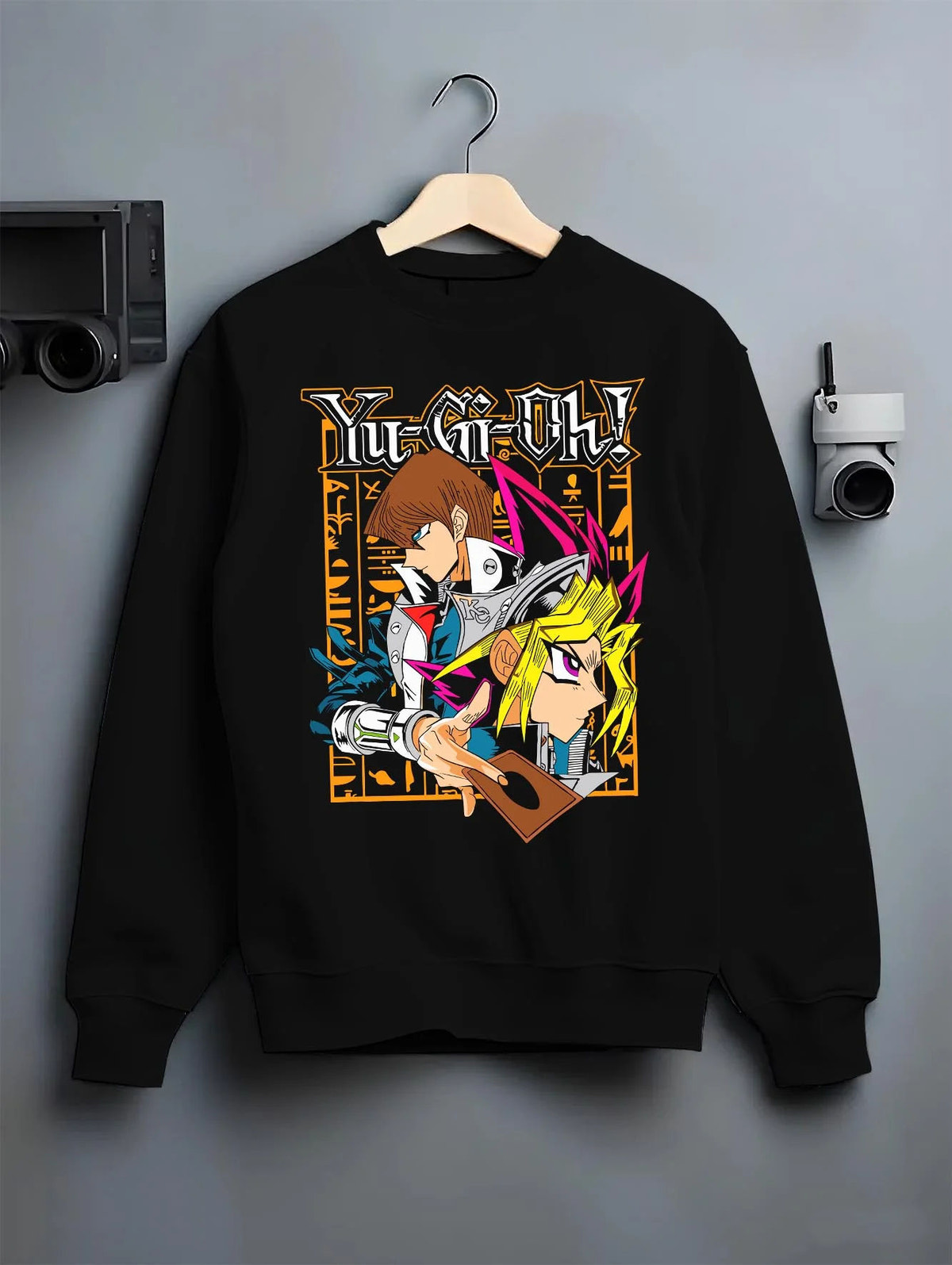 Black crewneck sweatshirt on hanger featuring Yu-Gi-Oh God Cards trio artwork.