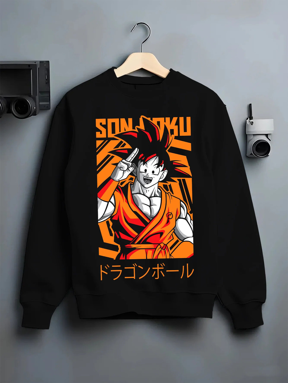 Black crewneck sweatshirt on hanger showing Young Goku from Dragon Ball: orange gi and raised hand