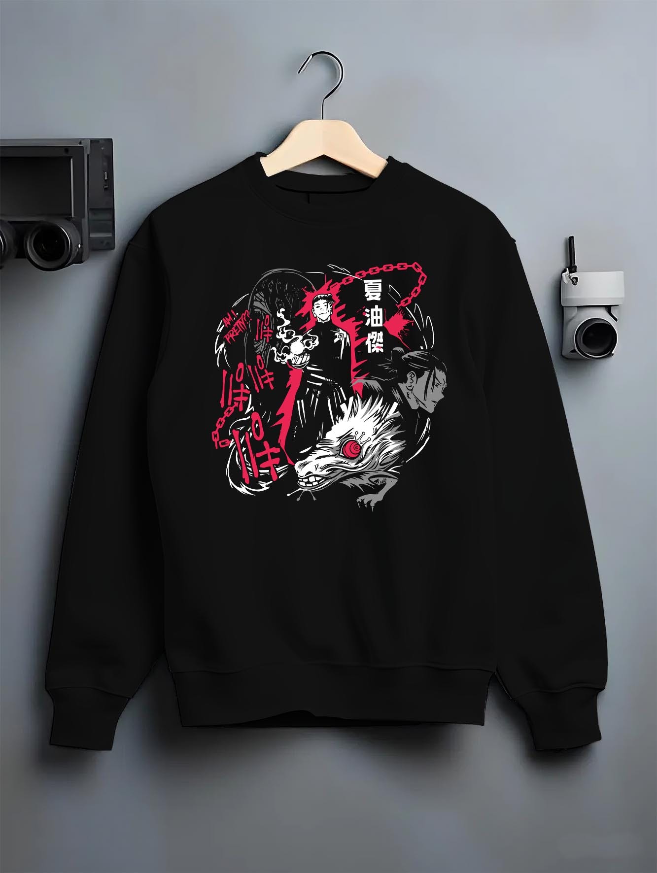 Black crewneck sweatshirt on a hanger against a grey wall, featuring Jujutsu Kaisen Suguru Geto dark manga panel inspired artwork with curse spirit and retro anime style.