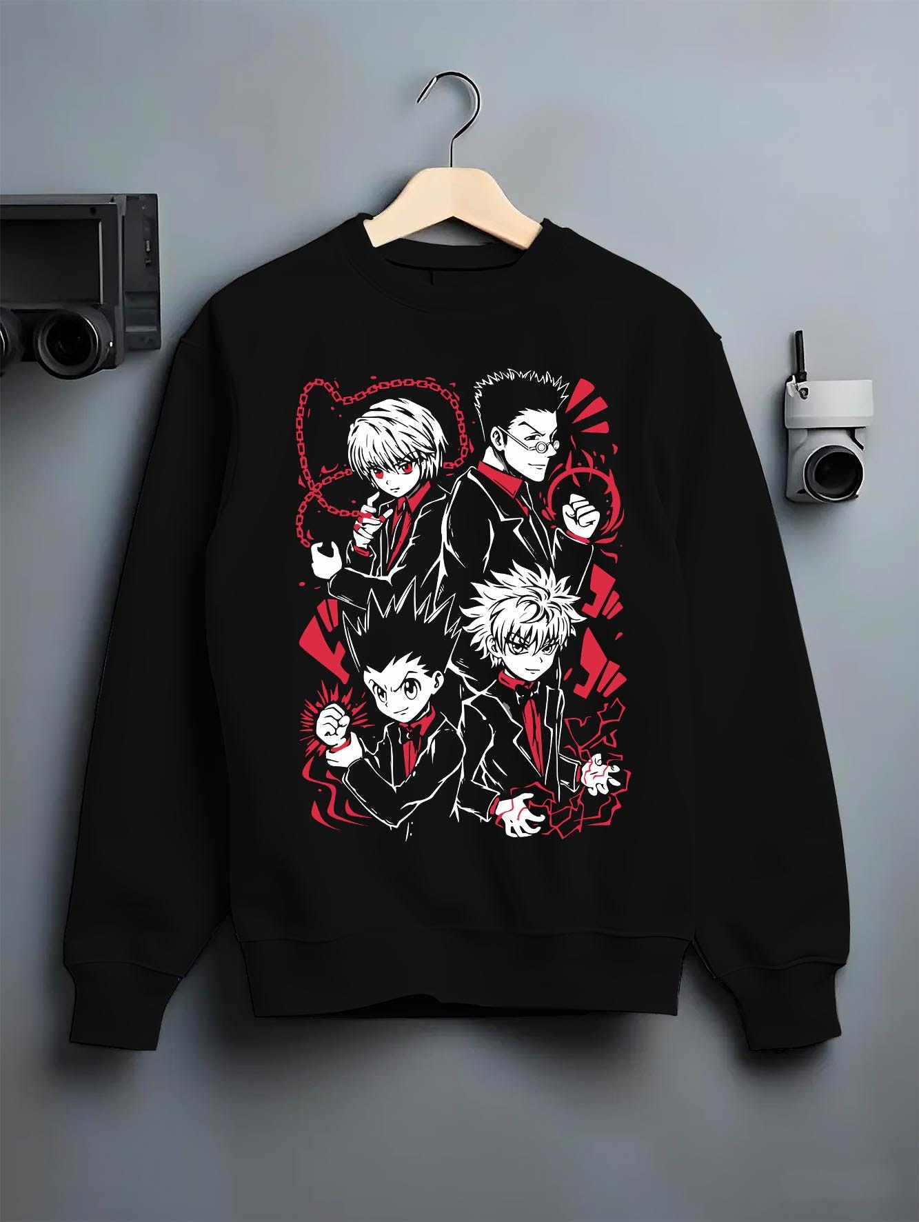 Black crewneck sweatshirt on a hanger against a grey wall, featuring Hunter x Hunter retro manga graphic with Gon, Killua, Kurapika, and Leorio in bold red suit artwork.