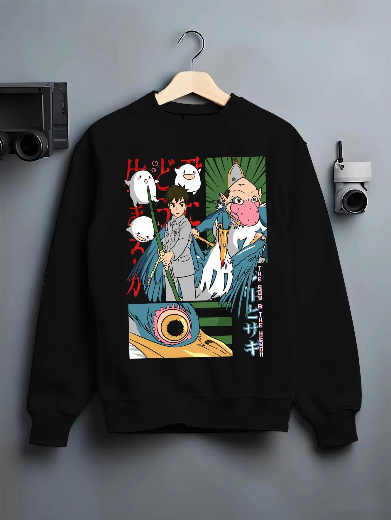 Black crewneck sweatshirt on hanger with The Boy And The Heron Hoodie Studio Ghibli Movie graphic nan anime design.