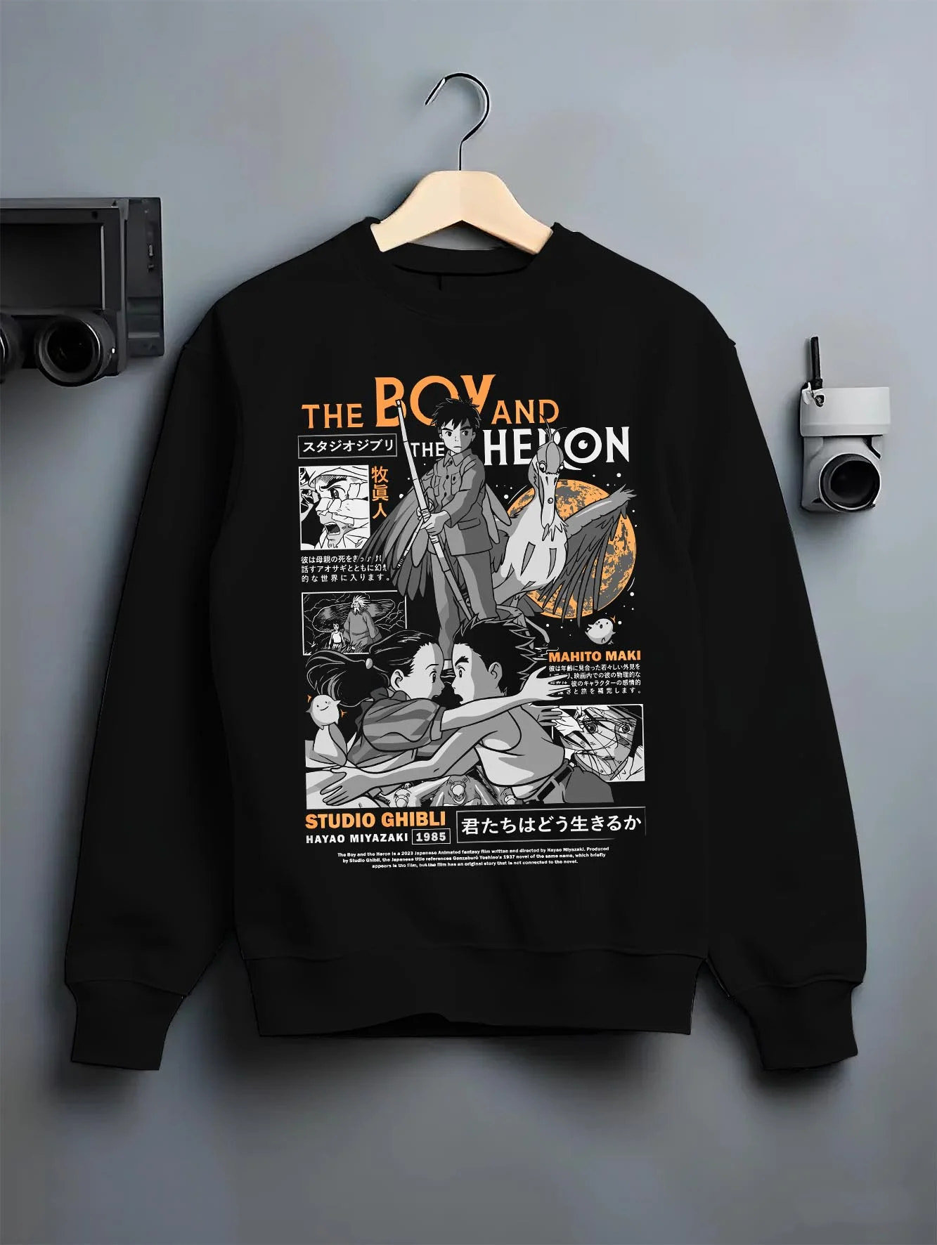 Black crewneck sweatshirt on hanger with The Boy And The Heron Hoodie Studio Ghibli Cover graphic nan anime design.