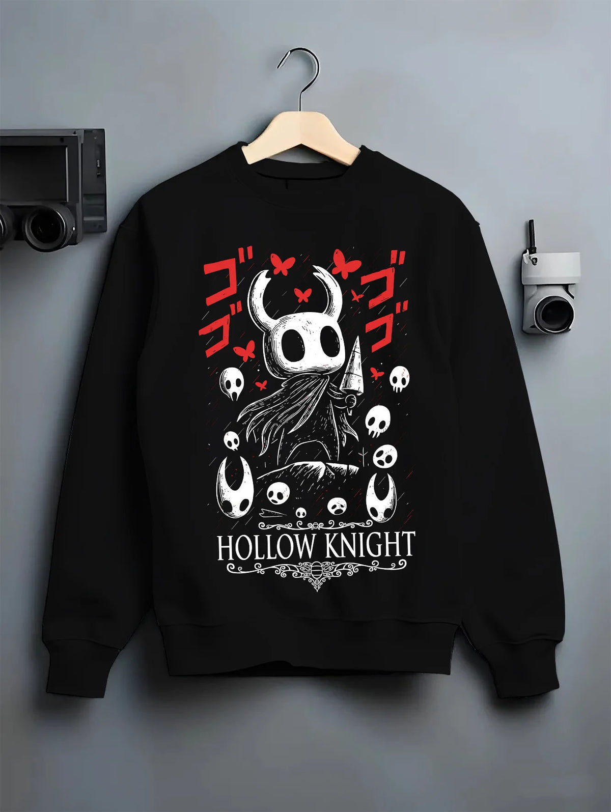 Black crewneck sweatshirt on hanger showing Hollow Knight: black-and-white knight heads