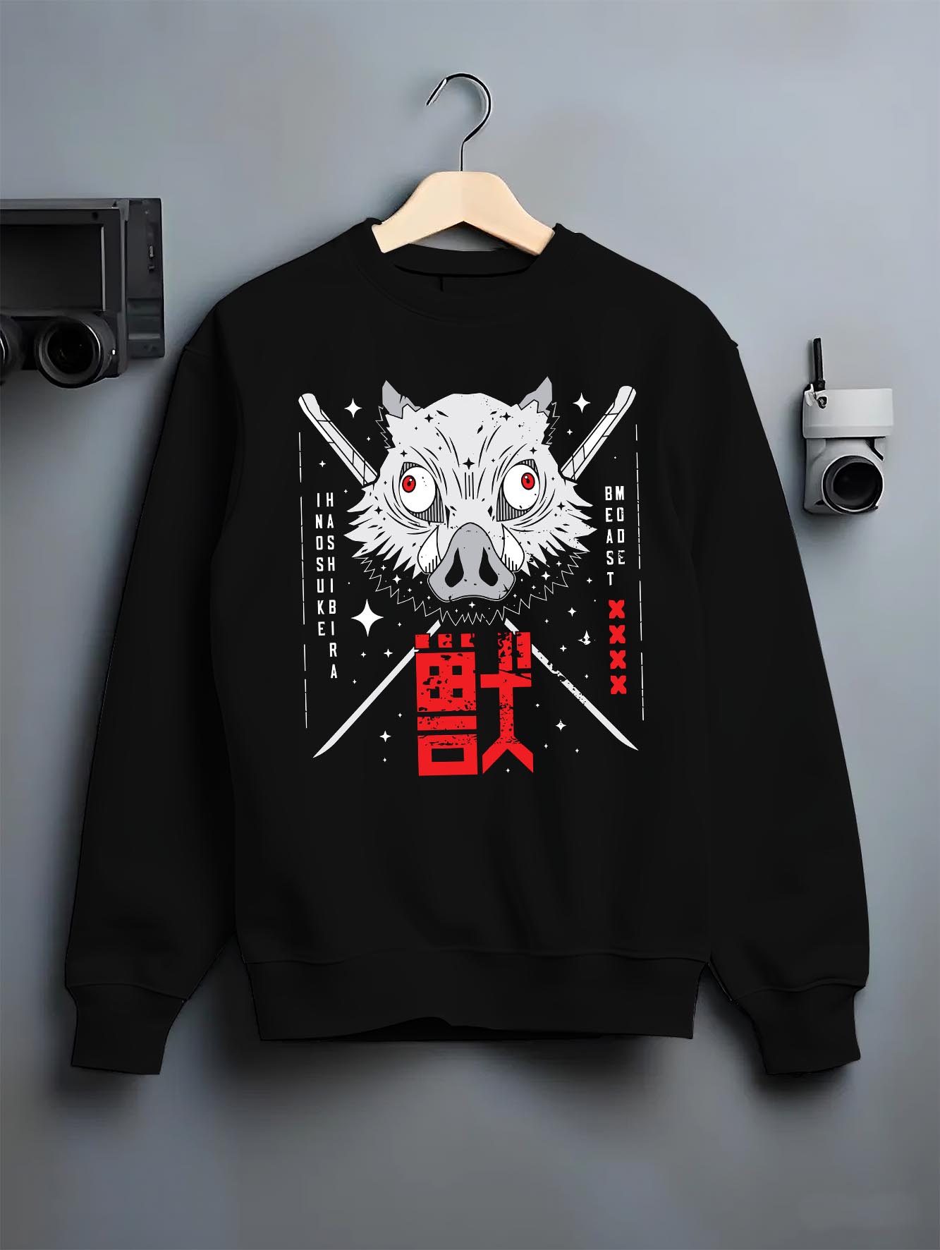 Black crewneck sweatshirt on a hanger against a grey wall, featuring Inosuke Hashibira anime poster inspired boar mask design with swords and bold red Japanese manga details.
