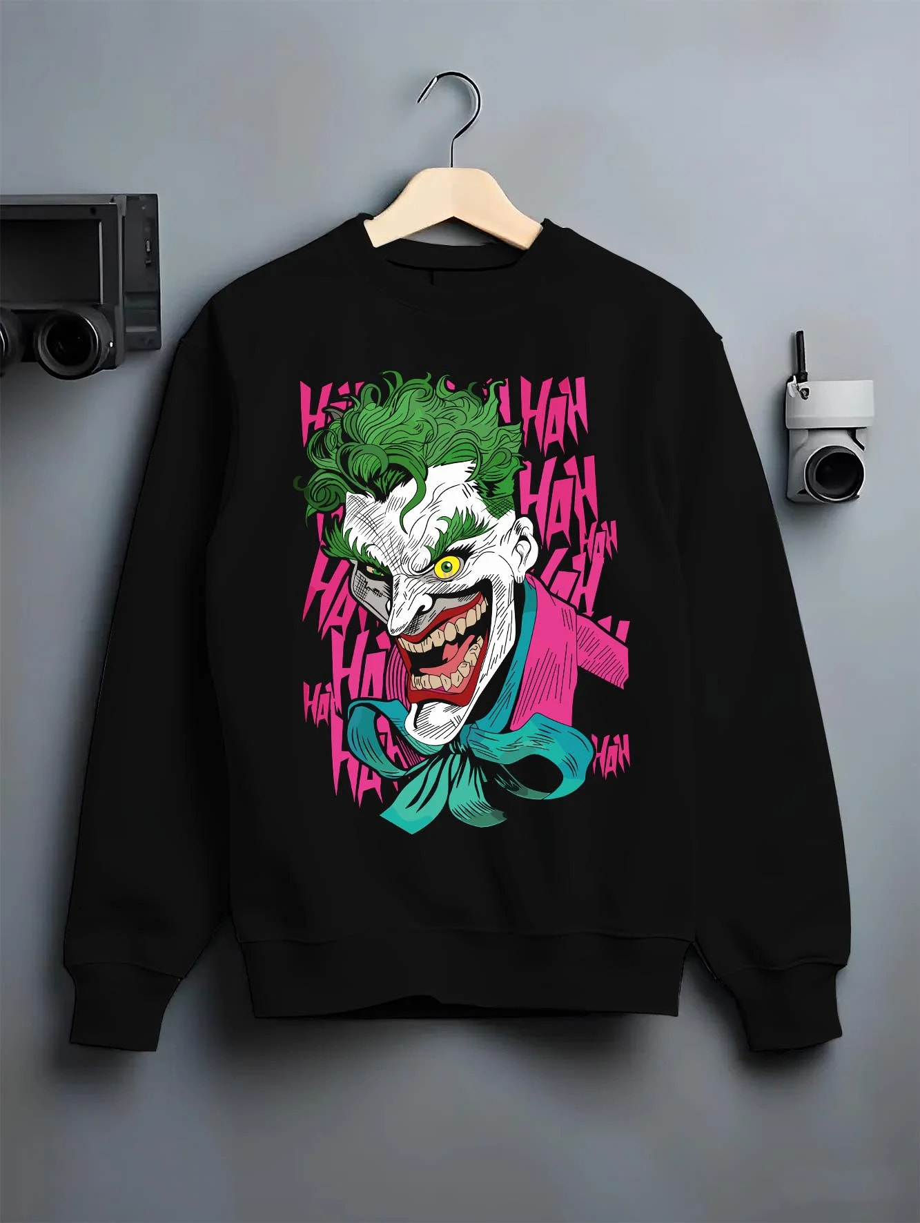 Black crewneck sweatshirt on hanger with Joker Hoodie Gotham Anime Inspired Laughing Villain Design graphic bold anime graphic.