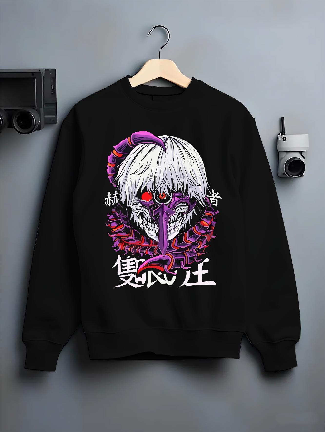 Black crewneck sweatshirt on a hanger against a grey wall, featuring Tokyo Ghoul Kaneki Ken dark manga panel artwork with centipede mask and retro anime aesthetic.