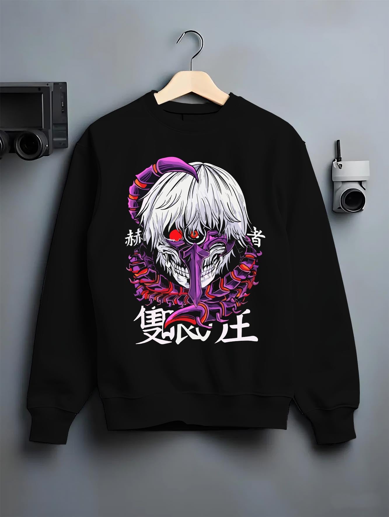 Black crewneck sweatshirt on a hanger against a grey wall, featuring Tokyo Ghoul Kaneki Ken dark manga panel artwork with centipede mask and retro anime aesthetic.