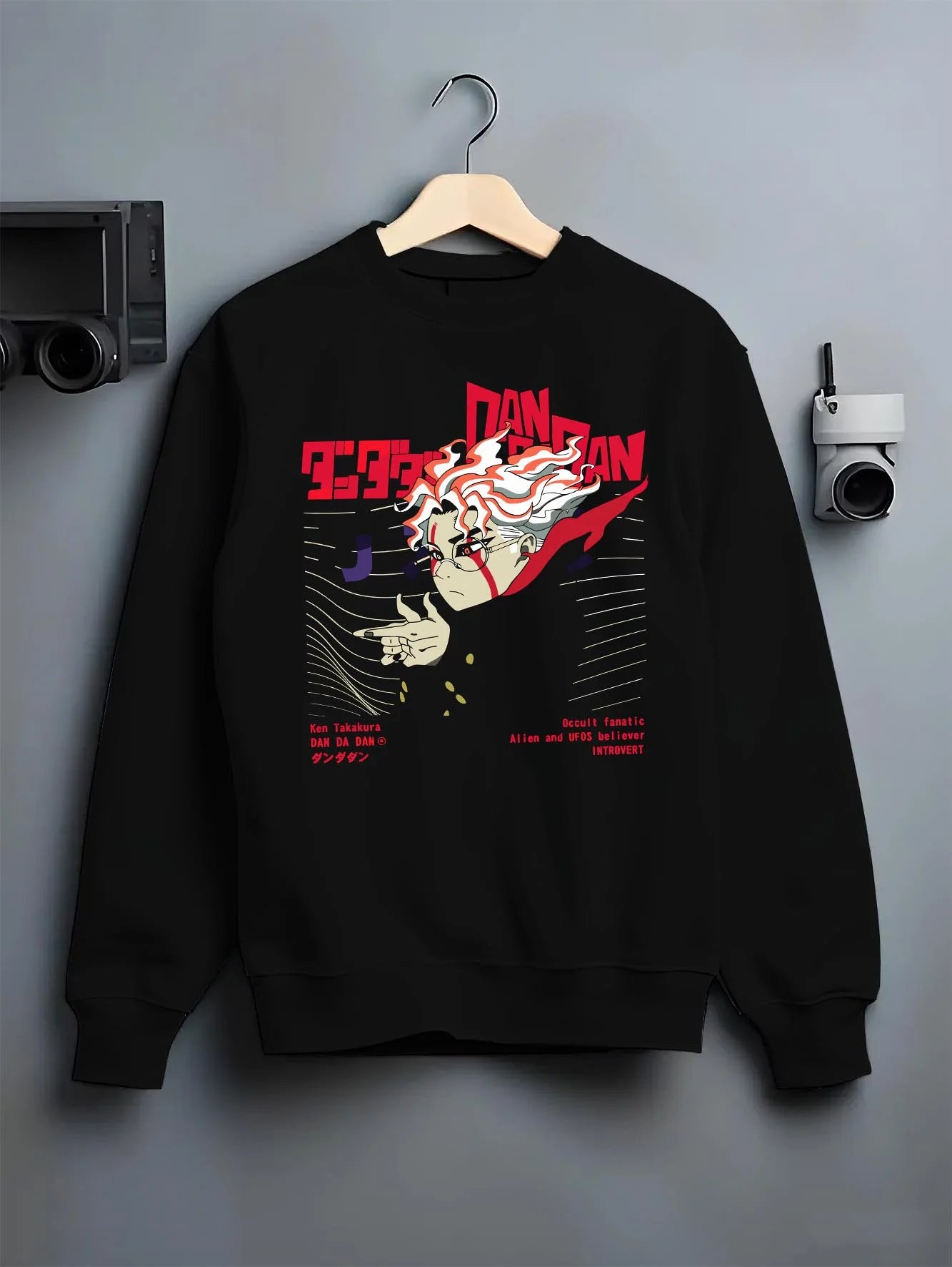 Black crewneck sweatshirt on hanger with Ken Takakura Dandadan Hoodie Occult UFO Believer Retro graphic premium wear.