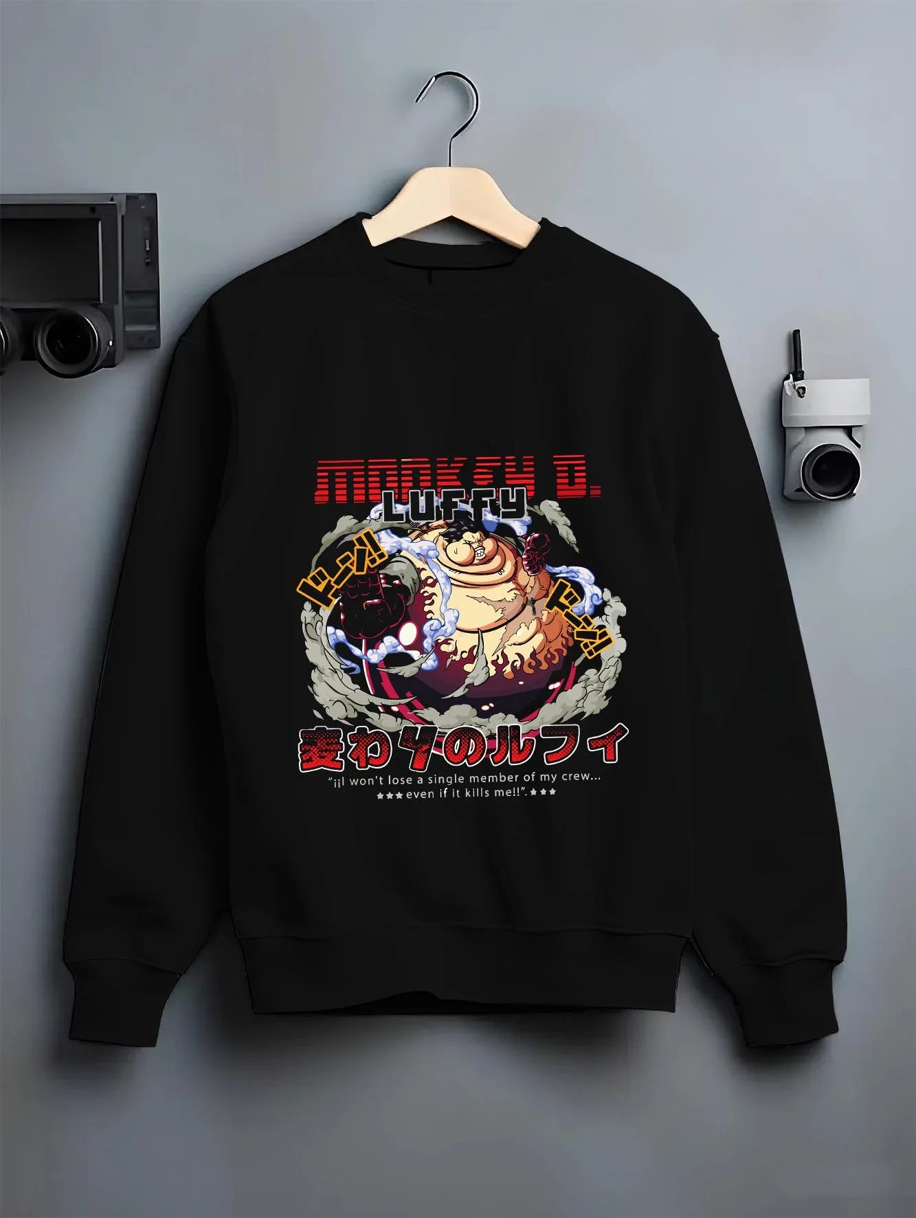 Black crewneck sweatshirt on a hanger against a grey wall, featuring nostalgic 90s inspired One Piece Luffy Gear Fourth design.