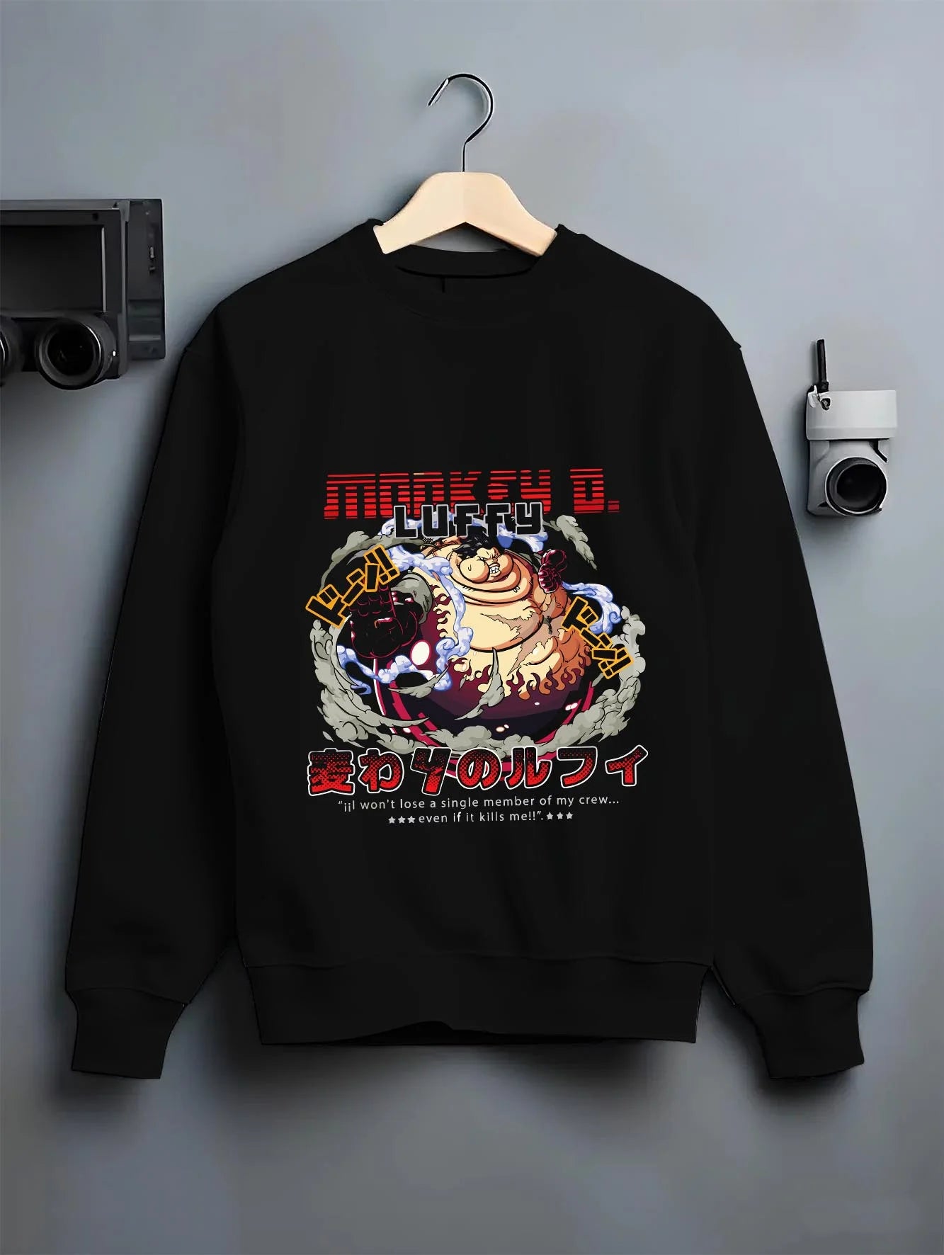 Black crewneck sweatshirt on a hanger against a grey wall, featuring nostalgic 90s inspired One Piece Luffy Gear Fourth design.
