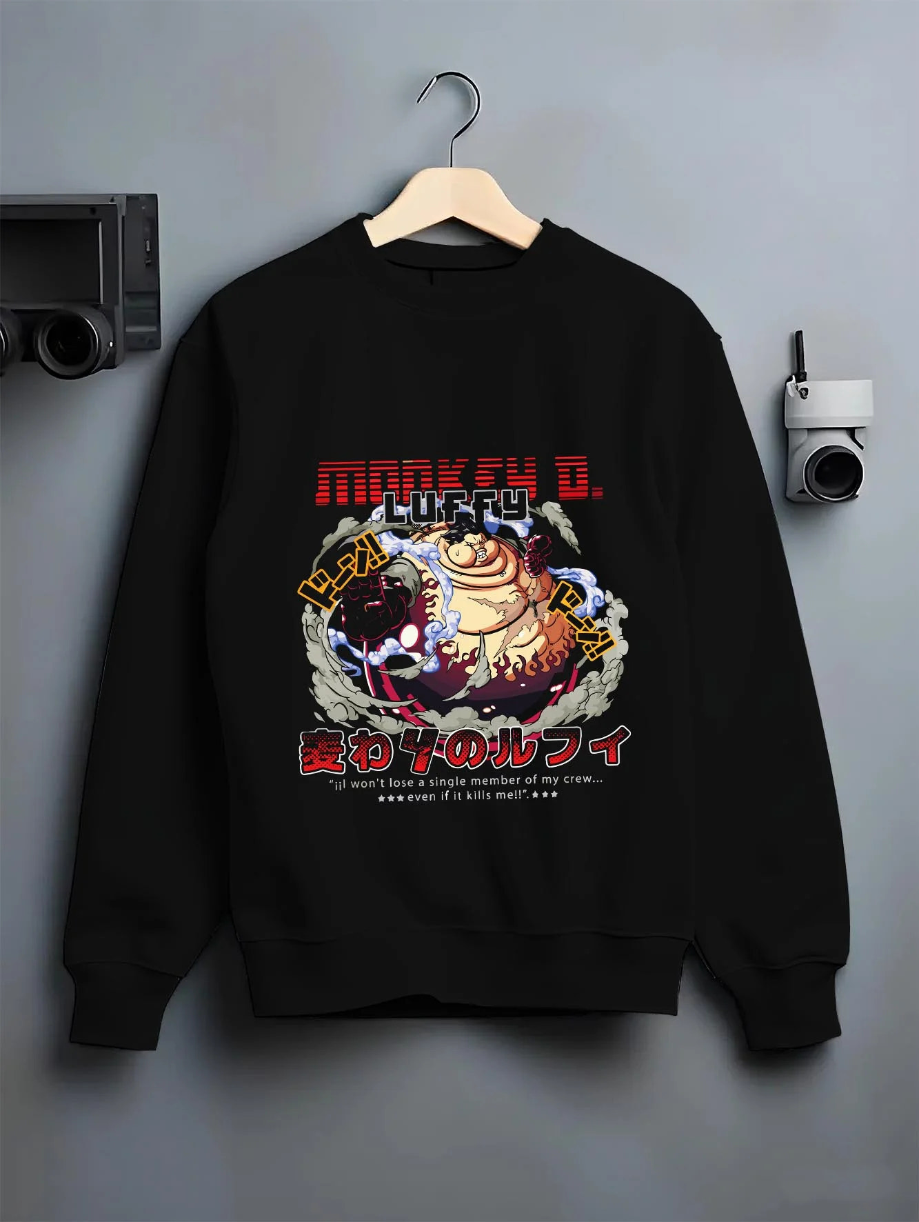 Black crewneck sweatshirt on a hanger against a grey wall, featuring nostalgic 90s inspired One Piece Luffy Gear Fourth design.