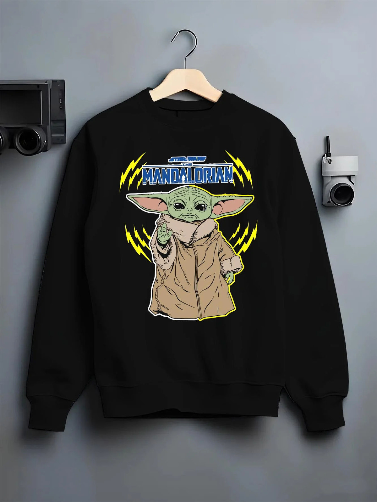 Black crewneck sweatshirt on hanger featuring Grogu from The Mandalorian artwork.