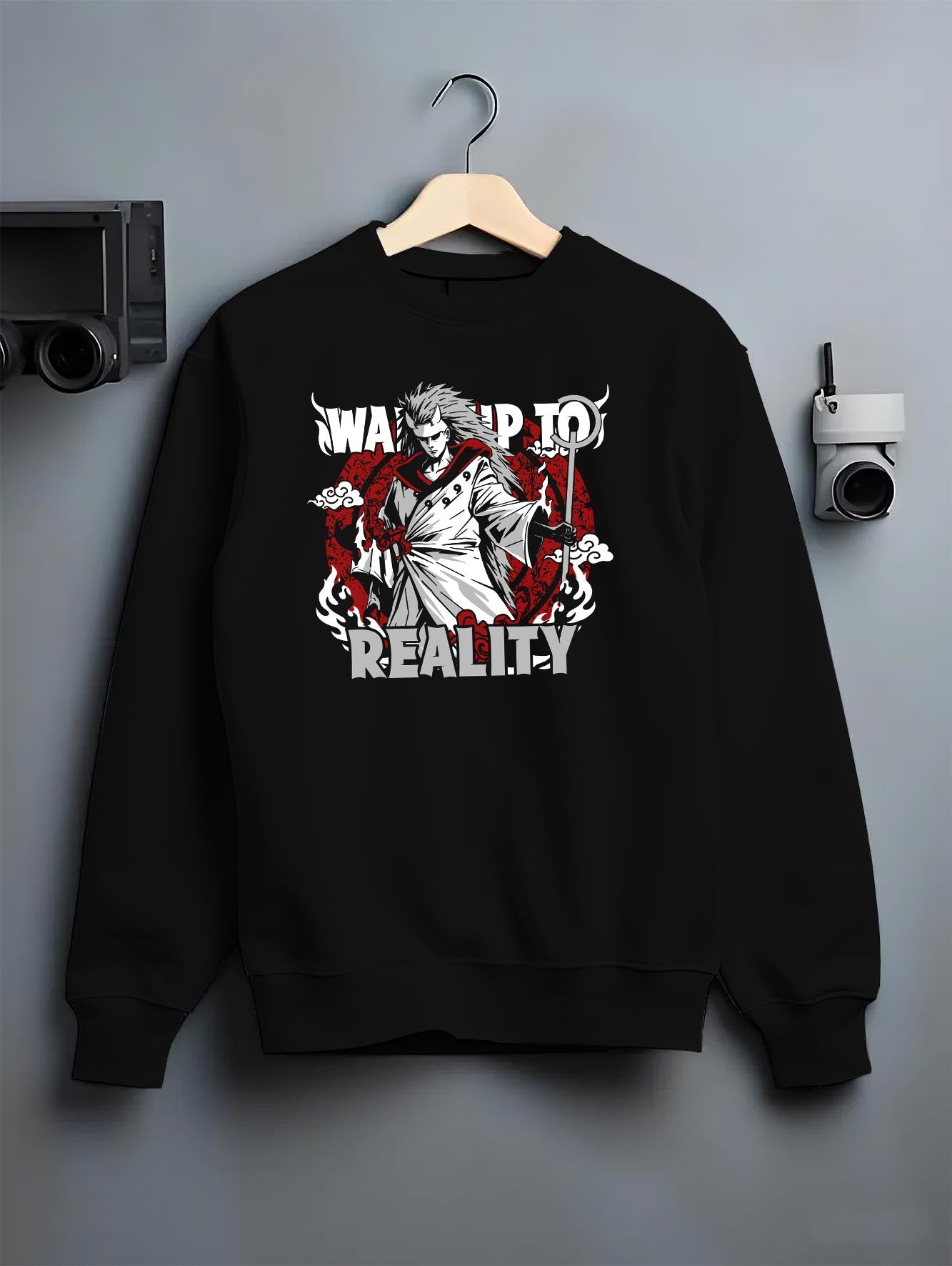 Black crewneck sweatshirt on a hanger against a grey wall, featuring Naruto Madara Uchiha anime poster inspired design with “Wake Up to Reality” slogan in retro manga style.