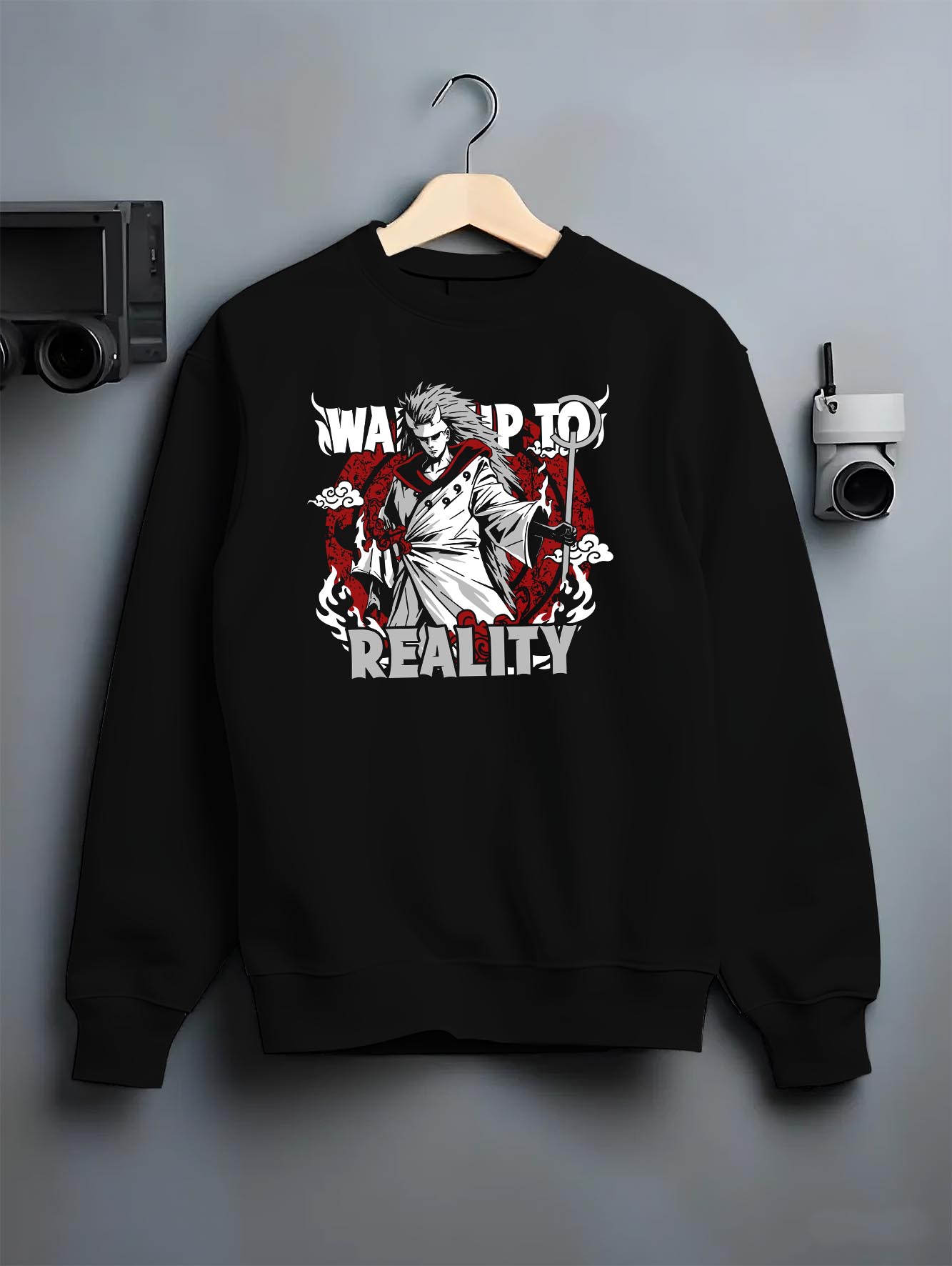 Black crewneck sweatshirt on a hanger against a grey wall, featuring Naruto Madara Uchiha anime poster inspired design with “Wake Up to Reality” slogan in retro manga style.