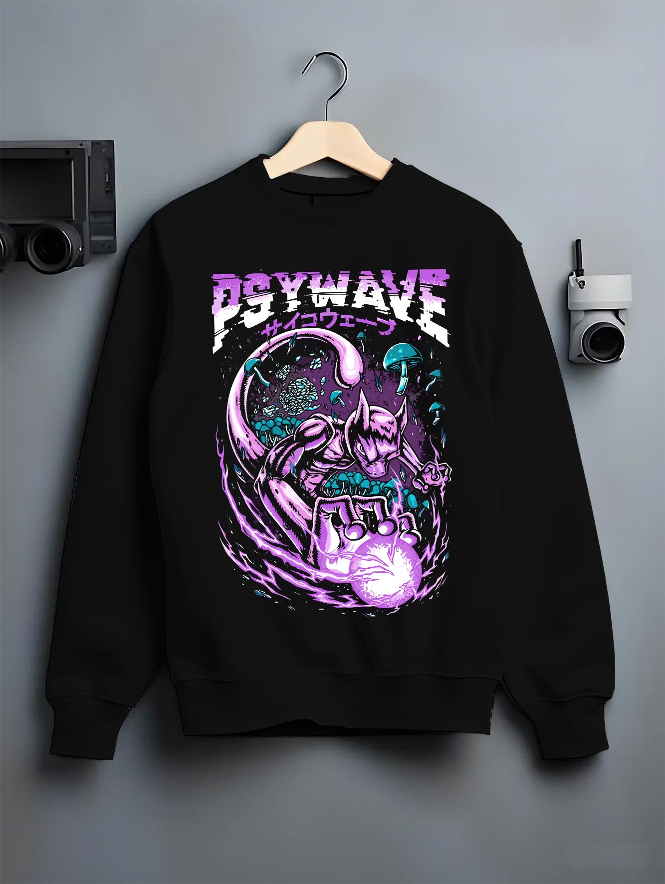 Black crewneck sweatshirt on a hanger against a grey wall, featuring Mewtwo modern streetwear graphic with neon purple psychic blast.