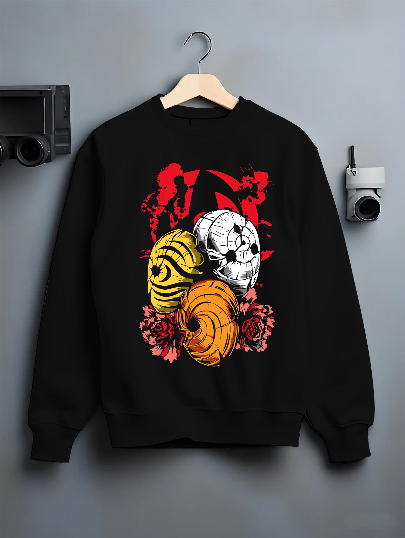 Black crewneck sweatshirt on a hanger against a grey wall, featuring Kakashi Hatake shonen battle character artwork with Susanoo flames and glowing manga detail.