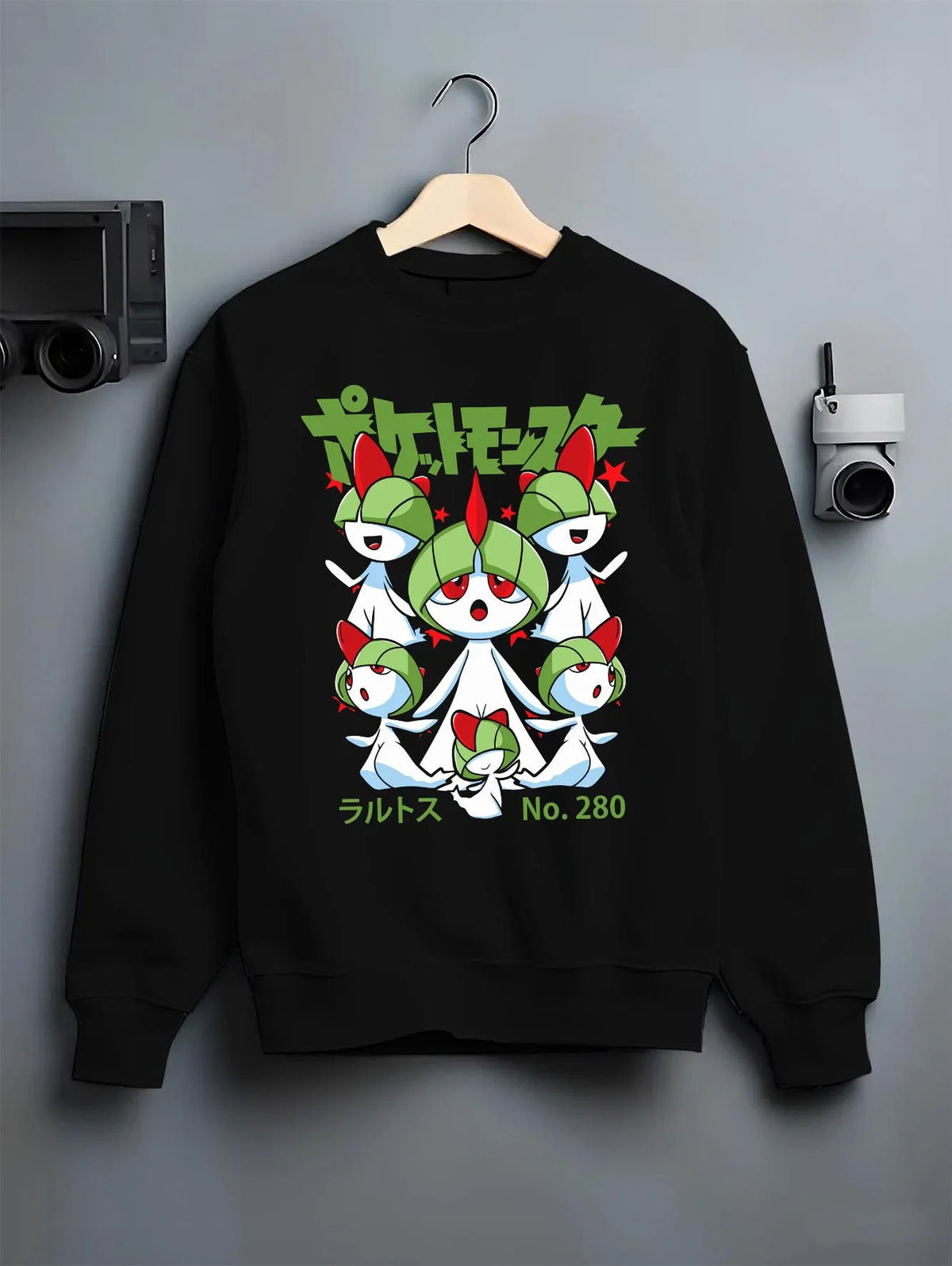 Black crewneck sweatshirt on hanger featuring Ralts psychic fairy evolution family Pokemon artwork.