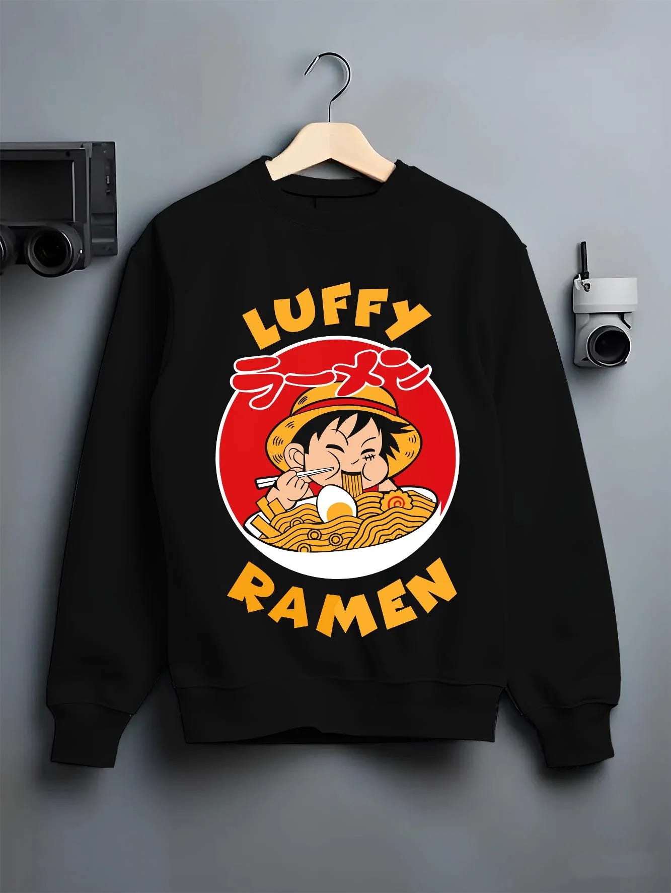 Black crewneck sweatshirt on hanger with Luffy Ramen Hoodie One Piece Pirate Food Design graphic bold anime graphic.