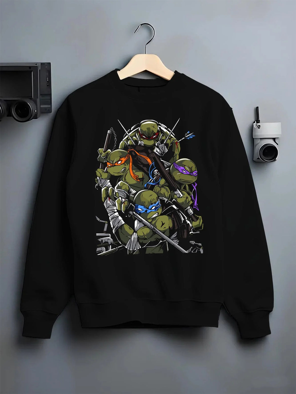 Black crewneck sweatshirt on hanger featuring Teenage Mutant Ninja Turtles sewer team TMNT artwork.