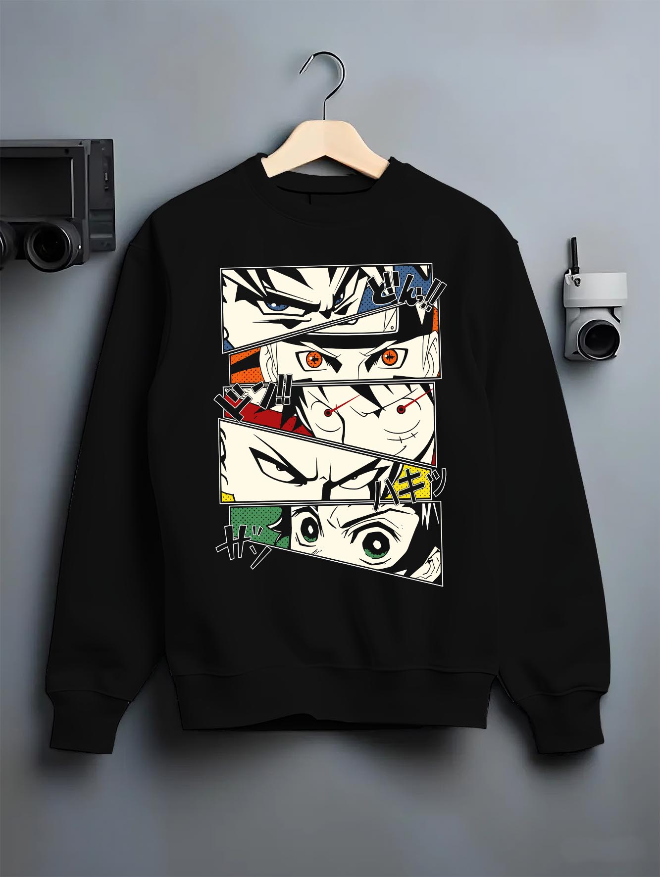 Black crewneck sweatshirt on a hanger against a grey wall, featuring retro streetwear manga collage of Goku, Naruto, Luffy, Saitama, and Tanjiro.