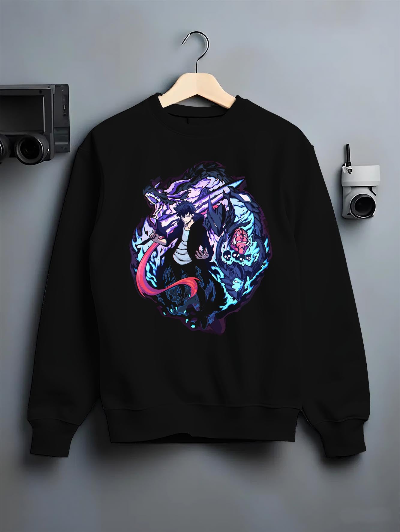 Black crewneck sweatshirt on a hanger against a grey wall, featuring Jinwoo Sung shonen battle character design with sword and neon shadow dragon style.