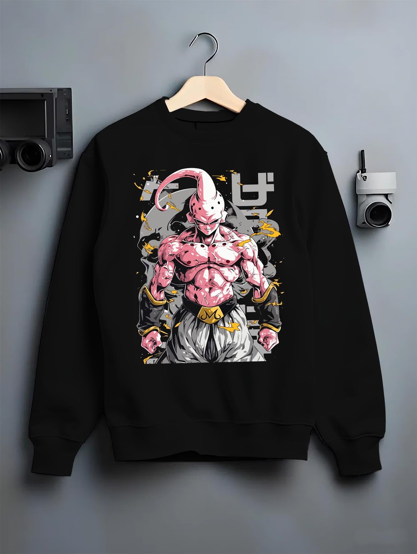 Black crewneck sweatshirt on a hanger against a grey wall, featuring Dragon Ball Majin Buu anime poster inspired design with shonen battle pose and lightning aura effects.