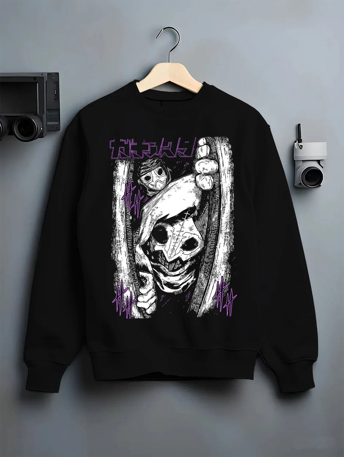 Black crewneck sweatshirt on hanger showing Tamsy from Gachiakuta: eerie close-up mask/pupil
