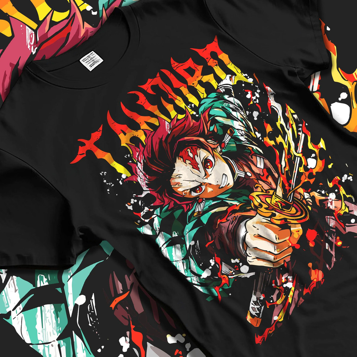 Black T-shirt laid flat with natural folds featuring Tanjiro Kamado flame sword Hinokami battle Demon Slayer artwork.