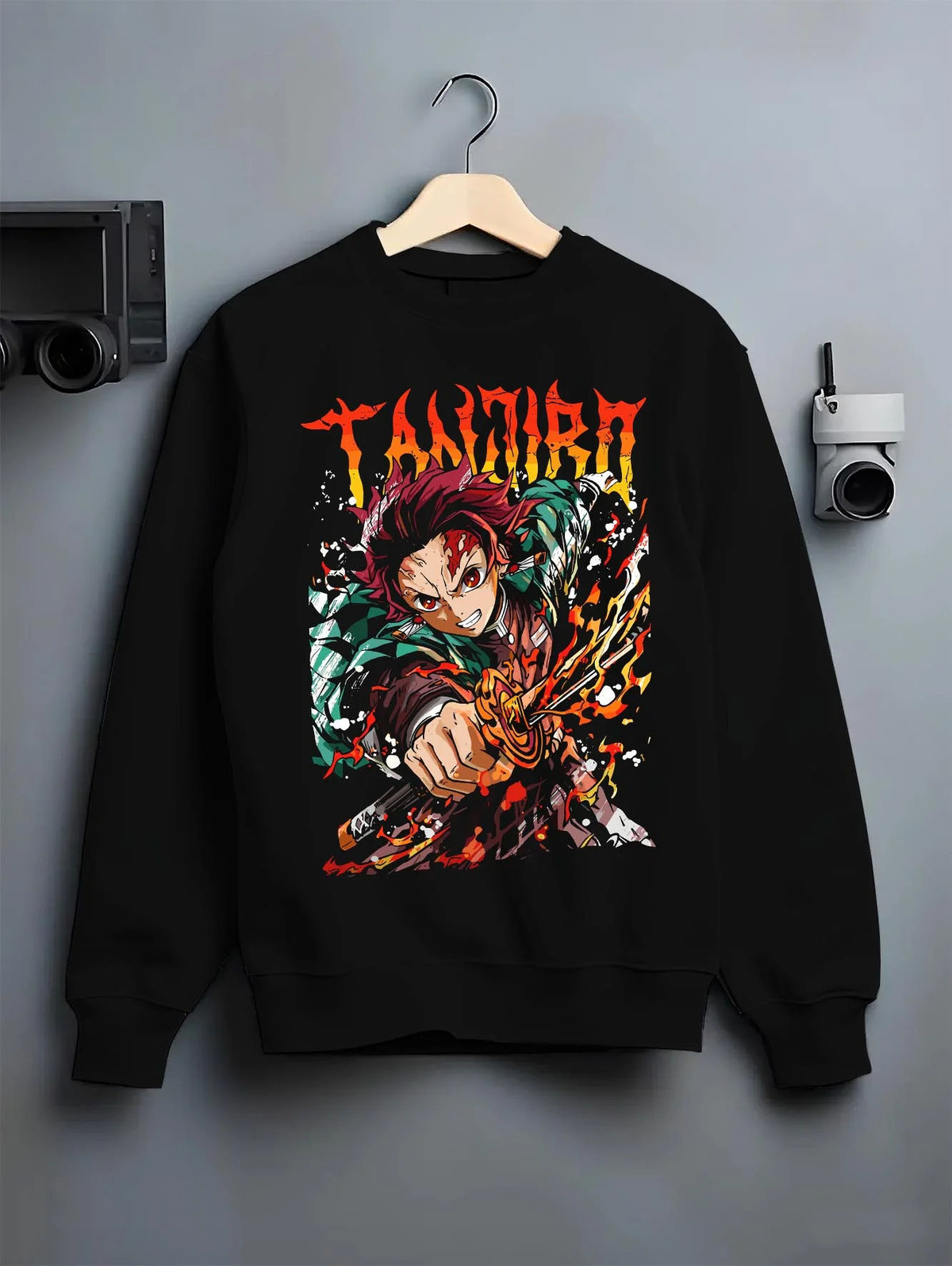 Black crewneck sweatshirt on hanger featuring Tanjiro Kamado flame sword Hinokami battle Demon Slayer artwork.