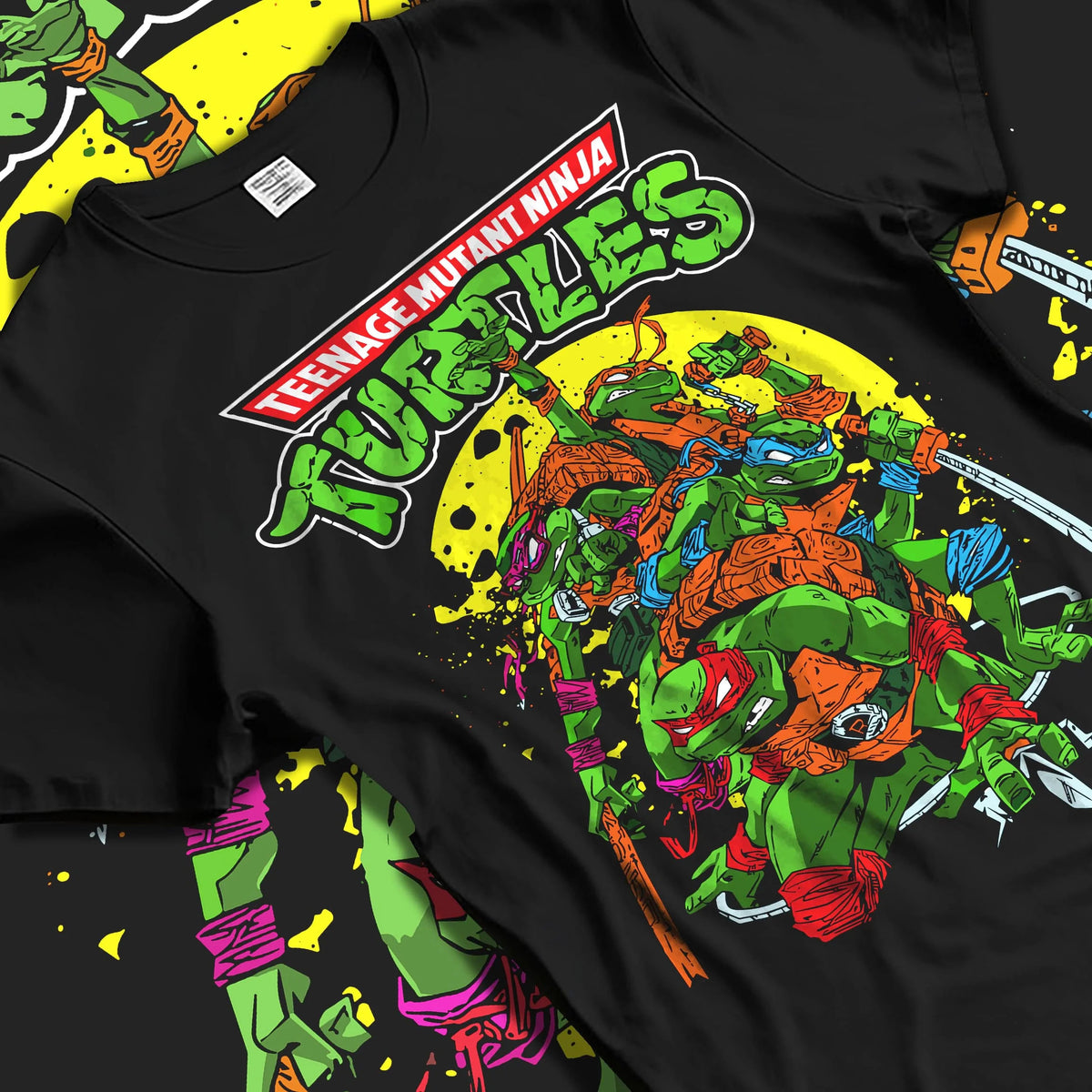 Black T-shirt laid flat with natural folds featuring Teenage Mutant Ninja Turtles heroes TMNT artwork.