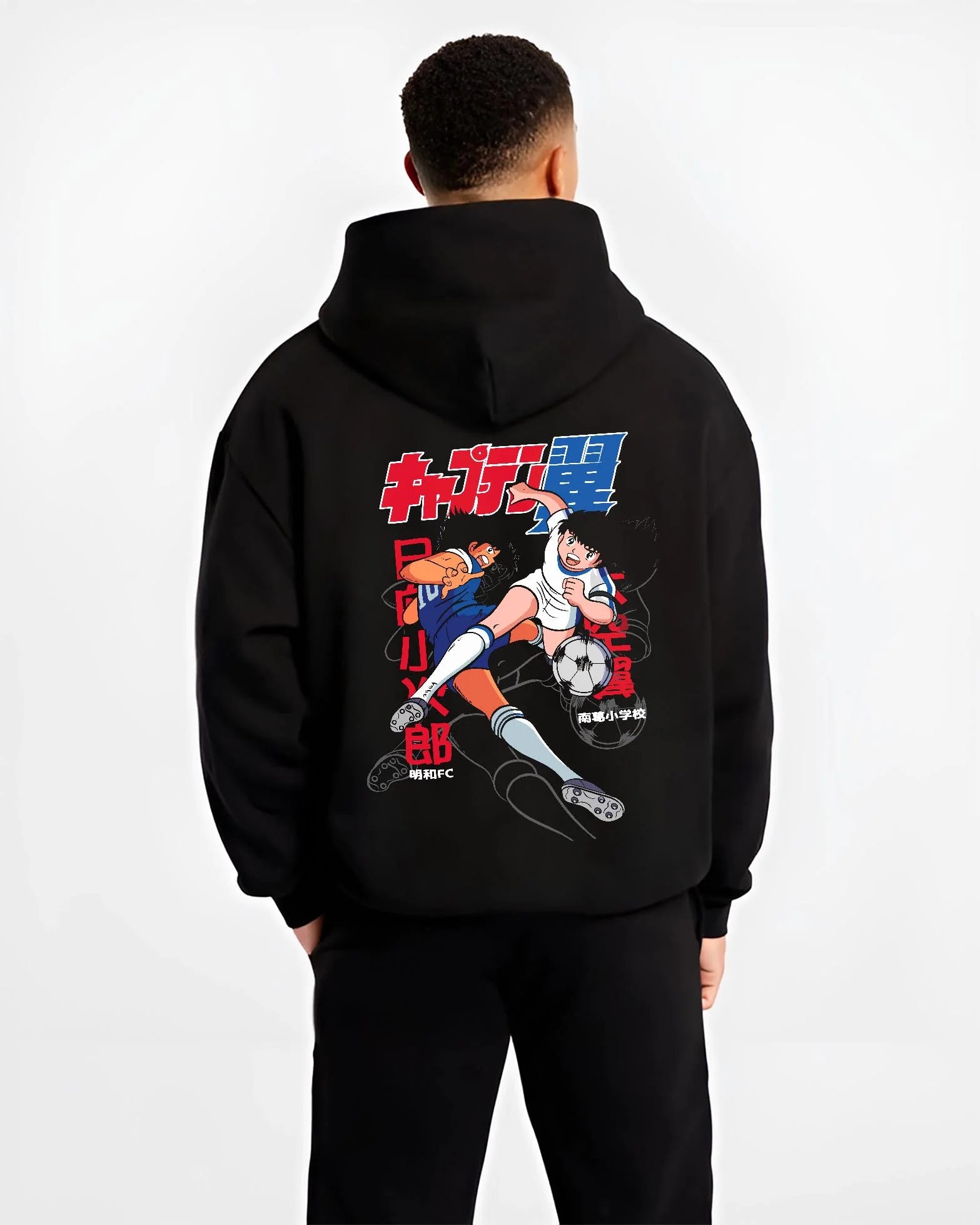 Black hoodie worn by male model, back view with Tsubasa Duo Hoodie Captain Tsubasa Soccer Team Play graphic premium wear.